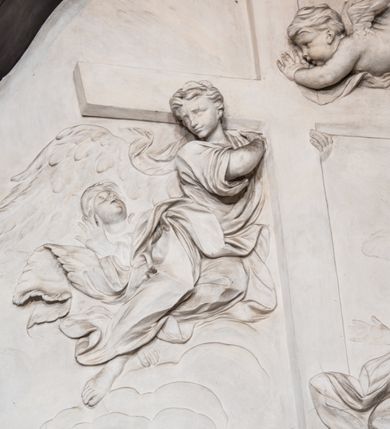 Zdjęcie nr 3: Ołtarz ustawiony na trójstopniowym podeście, prostopadłościenny, z antepedium z dekoracją w technice skaliola z pól geometrycznych dzielonych listwami i wypełniony drobnymi, wielobarwnymi kwiatkami. Za ołtarzem monumentalna nastawa utworzona z pilastrów i ukośnie ustawionych filarów stojących na wysokich postumentach. Ich trzony są kanelowane, a kapitele utworzone z jońskich wolut i przewiązanych taśmą lilijek. Nad kapitelami wznosi się belkowanie, nad zewnętrznymi pilastrami zwieńczone falistymi naczółkami, nad wewnętrznymi grupami uskrzydlonych puttów. Pośrodku znajduje się prostokątna wnęka zakończona łukiem półkolistym, nadwieszonym, w profilowanej ramie. W niej stiukowy relief przedstawiający Chwałę Krzyża Świętego adorowanego przez Matkę Boską z martwym Chrystusem spoczywającym na jej kolanach oraz przez św. Jana Ewangelistę odwróconego do widza plecami. Maria ukazana frontalnie, ubrana w rozłożystą suknię i  płaszcz zarzucony na głowę, z prawą ręką dotykająca głowy Jezusa, z lewą wyciągniętą do przodu. Jan przedstawiony w wykroku, z rękami wysuniętymi przed siebie, ubrany w suknię i płaszcz odkrywający lewy bark. Za Chrystusem ukazany anioł trzymający jego rękę. Nad nimi grupa aniołów unoszących krzyż. Ponad wnęką widnieje promienista, złocona gloria, z postacią Boga Ojca zasiadającego w chmurach, z gołębicą Ducha Świętego, puttami i główkami aniołów. Po bokach stoją figury św. Weroniki i św. Longina. Święta jest ubrana w długą, ekspresyjnie marszczoną suknię, w rękach trzyma rozłożoną chustę z twarzą Chrystusa. Longin jest przestawiony w zbroi rzymskiego legionisty, z długim, efektownie formowanym płaszczem, z lanca w prawej dłoni. 
