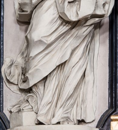 Zdjęcie nr 8: Ołtarz ustawiony na trójstopniowym podeście, prostopadłościenny, z antepedium z dekoracją w technice skaliola z pól geometrycznych dzielonych listwami i wypełniony drobnymi, wielobarwnymi kwiatkami. Za ołtarzem monumentalna nastawa utworzona z pilastrów i ukośnie ustawionych filarów stojących na wysokich postumentach. Ich trzony są kanelowane, a kapitele utworzone z jońskich wolut i przewiązanych taśmą lilijek. Nad kapitelami wznosi się belkowanie, nad zewnętrznymi pilastrami zwieńczone falistymi naczółkami, nad wewnętrznymi grupami uskrzydlonych puttów. Pośrodku znajduje się prostokątna wnęka zakończona łukiem półkolistym, nadwieszonym, w profilowanej ramie. W niej stiukowy relief przedstawiający Chwałę Krzyża Świętego adorowanego przez Matkę Boską z martwym Chrystusem spoczywającym na jej kolanach oraz przez św. Jana Ewangelistę odwróconego do widza plecami. Maria ukazana frontalnie, ubrana w rozłożystą suknię i  płaszcz zarzucony na głowę, z prawą ręką dotykająca głowy Jezusa, z lewą wyciągniętą do przodu. Jan przedstawiony w wykroku, z rękami wysuniętymi przed siebie, ubrany w suknię i płaszcz odkrywający lewy bark. Za Chrystusem ukazany anioł trzymający jego rękę. Nad nimi grupa aniołów unoszących krzyż. Ponad wnęką widnieje promienista, złocona gloria, z postacią Boga Ojca zasiadającego w chmurach, z gołębicą Ducha Świętego, puttami i główkami aniołów. Po bokach stoją figury św. Weroniki i św. Longina. Święta jest ubrana w długą, ekspresyjnie marszczoną suknię, w rękach trzyma rozłożoną chustę z twarzą Chrystusa. Longin jest przestawiony w zbroi rzymskiego legionisty, z długim, efektownie formowanym płaszczem, z lanca w prawej dłoni. 
