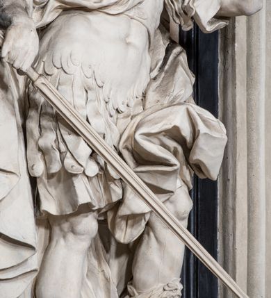 Zdjęcie nr 11: Ołtarz ustawiony na trójstopniowym podeście, prostopadłościenny, z antepedium z dekoracją w technice skaliola z pól geometrycznych dzielonych listwami i wypełniony drobnymi, wielobarwnymi kwiatkami. Za ołtarzem monumentalna nastawa utworzona z pilastrów i ukośnie ustawionych filarów stojących na wysokich postumentach. Ich trzony są kanelowane, a kapitele utworzone z jońskich wolut i przewiązanych taśmą lilijek. Nad kapitelami wznosi się belkowanie, nad zewnętrznymi pilastrami zwieńczone falistymi naczółkami, nad wewnętrznymi grupami uskrzydlonych puttów. Pośrodku znajduje się prostokątna wnęka zakończona łukiem półkolistym, nadwieszonym, w profilowanej ramie. W niej stiukowy relief przedstawiający Chwałę Krzyża Świętego adorowanego przez Matkę Boską z martwym Chrystusem spoczywającym na jej kolanach oraz przez św. Jana Ewangelistę odwróconego do widza plecami. Maria ukazana frontalnie, ubrana w rozłożystą suknię i  płaszcz zarzucony na głowę, z prawą ręką dotykająca głowy Jezusa, z lewą wyciągniętą do przodu. Jan przedstawiony w wykroku, z rękami wysuniętymi przed siebie, ubrany w suknię i płaszcz odkrywający lewy bark. Za Chrystusem ukazany anioł trzymający jego rękę. Nad nimi grupa aniołów unoszących krzyż. Ponad wnęką widnieje promienista, złocona gloria, z postacią Boga Ojca zasiadającego w chmurach, z gołębicą Ducha Świętego, puttami i główkami aniołów. Po bokach stoją figury św. Weroniki i św. Longina. Święta jest ubrana w długą, ekspresyjnie marszczoną suknię, w rękach trzyma rozłożoną chustę z twarzą Chrystusa. Longin jest przestawiony w zbroi rzymskiego legionisty, z długim, efektownie formowanym płaszczem, z lanca w prawej dłoni. 
