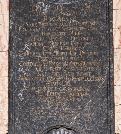 Zdjęcie nr 3: Epitafium w kształcie pionowej tablicy, ujętej spływami wolutowymi z kampanulami, z owalnym polem na portret, zwieńczonej profilowanym, falistym gzymsem. U dołu kartusz z herbem Prus III pod kapeluszem kanonickim zwieńczony muszlą. Portret ujęty profilowaniem z dwiema taśmami, przedstawia mężczyznę w popiersiu, w białym kołnierzu z turkusowymi befkami, z głową ukazaną w trzech czwartych, zwróconą lekko w lewo. Jego twarz jest pełna, nos wydatny, prosty, oczy otwarte, spoglądają wprost, usta zamknięte, wyraziście zaznaczone czerwienią, włosy krótkie, kręcone na bokach, odsłaniające niewielkie zakola. Tło nieokreślone, w tonacji brązów. Tablica z inskrypcją prostokątna, o zaoblonych, ujętych ceownicami narożach i wyciętych niemal półkoliście krótszych bokach, w niej złocona inskrypcja: "D(EO) O(PTIMO) M(AXIMO) / IOANNI IOSEPHO / RYGALSKI /  SACRAE THEOLOGIAE DOCTRO I PROFESSORI / ECCLESIAE COLLEGIATAE SANCTI FLORIANI CUSTODI / UNIVERSITATIS ALMAE / FILIO PATRI RECTORI / SAPIENTI MUNIFICIO MORIGERO / CARO MAGNIFICO / QUI TURRES ISTIUS TEMPLI AERE PANNONIO/ TECTAS ASTRIS INTULIT. / COLLEGIATAS et PAROCHIALEM VETERO CORCINENSEM / QUAS REXIT et ORNAVIT ECCLESIAS / SACRA SUPELLECTILI DITAVIT. / ANNO SALUTIS GENERIS HUMANI MDCCLXXIX / AETATIS LXI / VIAM UNIVERSAE CARNIS INGRESSO / FIDI DOLENTES EXECUTORES / AMORIS MEMORIAE ERGO / POSUERE / Quid Solutis est Beatius curis / Cum mensonus reponit ac peregrino / Labore fessi venimus Patriam ad nostram / Hoc est quod unum est pio laboribus antis!". 
