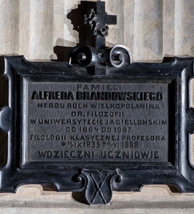 Zdjęcie nr 1: Epitafium w kształcie leżącego prostokąta w ramie o lekko wklęsłej powierzchni  z uszakami, z herbem Uniwersytetu Jagiellońskiego u dołu i krzyżem z koroną cierniową osadzonym w wolucie. W polu inskrypcja: „PAMIĘCI / ALFREDA BRANDOWSKIEGO / HERBU ROCH WIELKOPOLANINA / D(OKTO)R(A) FILOZOFII / W UNIWERSYTECIE JAGIELLOŃSKIM / OD 1864 DO 1887 / FILOLOGII KLASYCZNEJ PROFESORA / *11/IX 1835 +4/VI 1888 / WDZIĘCZNI UCZNIOWIE”.