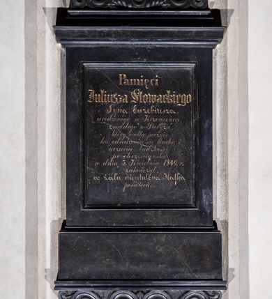 Zdjęcie nr 1: Epitafium w kształcie tablicy wspartej na wysokim cokole podpartym dwiema stykającymi się wolutami, zwieńczonej profilowanym gzymsem, na którym okrągły medalion, ujęty liśćmi i wolutami. W medalionie płaskorzeźbiona głowa poety ukazana z lewego profilu twarz wyrazista, z dużym nosem, otwartymi oczami, kręconymi włosami. Wzdłuż krawędzi inskrypcja „JULIUSZ SŁOWACKI / WŁADYSŁAW OLESZCZYŃSKI F(ECIT) / PARYZ [...]”. W polu tablicy inskrypcja „Pamięci / Juliusza Słowackiego / Syna Euzebiusza, / urodzonego w Krzemieńcu, / zmarłego w Paryżu, / który walkę poezyi / ku odrodzeniu się ducha i / uczucia ludzkości / po chrześciańsku / w dniu 3. Kwietnia 1849. r(oku) / zakończył, / w żalu nieutulona Matka / poświęca.”. W prawym dolnym rogu cokołu sygnatura „E(dward) Stehlik.” 