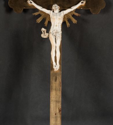 Zdjęcie nr 2: Rzeźba pełna, złożona z trzech ciosów – korpusu i dwóch rąk. Chrystus w typie Cristo vivo, przybity do krzyża trzema gwoździami jest ukazany w lekkim zwisie, z nieznacznie przegiętym ciałem i z szeroko rozłożonymi rękami. Jego głowa jest lekko odchylona do tyłu i nieznacznie przegięta w prawo, wzrok wznosi ku górze, usta szeroko otwarte z widocznym uzębieniem, wokół brody krótki zarost, a na głowie układające się faliście włosy, sięgające ramion. Anatomia ciała oddana poprawnie, z wypiętą klatką piersiową i umięśnionymi smukłymi nogami z krzyżującymi się stopami; na biodrach perizonium podwieszone na podwójnym, skręconym sznurze, z odsłoniętym prawym biodrem i swobodnie powiewającą z prawej strony połą materii. Krzyż o ramionach zakończonych trójlistnie, z glorią promienistą na skrzyżowaniu belek. Na górnej belce titulus z literami „IN/RI”. 
