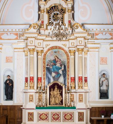 Zdjęcie nr 1: Ołtarz architektoniczny, jednokondygnacyjny, jednoosiowy, ze zwieńczeniem. Prostopadłościenny ołtarz, z antepedium artykułowanym 3 płycinami o dekoracyjnym wykroju, wtopiony jest z dolną partią, zryzalitowanego cokołu retabulum, której układ powtarza także górna partia cokołu. Część środkowa ujęta jest trzema parami kolumn korynckich, z których środkowe są wysunięte i ustawione na tle filarów. Podpory wspierają wyłamujące się ponad nimi, przerwane w partii architrawu i fryzu belkowanie. Druga kondygnacja jest w formie stojącego prostokąta ujętego parą ustawionych na cokołach kolumienek wspierających przerwane, wyłamujące się ponad nimi belkowanie. Dodatkowo ujmuje ją para spływów wolutowych oraz przerwany, wolutowy przyczółek. Zwieńczenie zamknięte jest parą stykających się wolut oraz ujęte przerwanym przyczółkiem wolutowym. Szczyt jest w formie ażurowej ornamentyki akantowo-rocaille’owej. W polu środkowym retabulum jest obraz w kształcie stojącego prostokąta zamkniętego półkoliście z przedstawieniem Matki Boskiej Różańcowej ze św. Dominikiem i św. Małgorzatą Alacoque. W polu zwieńczenia profilowana rama w kształcie prostokąta z uszakami w narożach, zamkniętego łukiem odcinkowym, z ażurowym monogramem maryjnym pośrodku, ujętym wieńcem obłoków i promienistą glorią. Retabulum zdobi stylizowana ornamentyka roślinna w postaci liści akantu i  dziewięćsiłu w formie rozet w płycinach antepedium i górnej partii cokołu retabulum oraz we fryzie. Nasada trzonów kolumn ujęta liśćmi akantu i gałązkami róż. Gzyms belkowania zdobi motyw astragalu. Struktura ołtarza utrzymana jest odcieniu kremowym, detal architektoniczny i ornamentyka częściowo są polichromowane w kolorze czerwonym oraz złocone.  