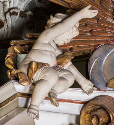 Zdjęcie nr 6: Ołtarz architektoniczny, jednokondygnacyjny, jednoosiowy, ze zwieńczeniem. Ołtarz prostopadłościenny, murowany. Retabulum o strukturze wklęsłej wzdłuż osi pionowej osadzone na niewysokim, cokole zryzalitowanym w formie pary impostów. Gzyms cokołu pośrodku ma formę półkolistego łuku nadwieszonego. Część środkowa ujęta parą wąskich filarów, licami zwróconych ukośnie na zewnątrz, wspierających wydatny gzyms osadzony na parze spływów wolutowych. Pola cokołu retabulum zdobione ornamentyką roślinną. Na impostach para figur aniołków, stojący po lewej stronie w lewej dłoni ma zwój z napisem „PATRZ / SWEGO / A NIE / PRAGNIJ / CUDZEGO”, stojący po prawej trzyma lewą ręką wspartą na podłożu tarczę z napisem „ZLE / NABYTE / NIE / BĘDZIE / DOBRZE / SPOŻYTE”. Między impostami płycina w kształcie prostokąta leżącego o wklęsłych górnych narożach i zamkniętego półkolistym łukiem nadwieszonym. W dolnej partii retabulum para uskrzydlonych główek anielskich dołem ujętych liśćmi akantu. Lica filarów zdobione motywem kampanuli. W partii belkowania, pośrodku motyw akantowego kartusza z napisem „VENI / CORONABE/RIS.”, ujętego górą, dołem i po bokach motywami uskrzydlonych główek anielskich. Zwieńczenie w formie promienistej glorii z koroną osadzoną na obłokach. Całość flankuje para siedzących na gzymsie aniołów w dynamicznych pozach. Pole części środkowej w kształcie stojącego prostokąta ujętego górą i dołem parą zwróconych do siebie półkolistych łuków nadwieszonych z uskokami, ujęte profilowaną, złoconą ramą. Wewnątrz obraz z wizerunkiem Matki Boskiej. Struktura polichromowana w kolorze białym, detal architektoniczny i ornamentyka złocone i srebrzone.