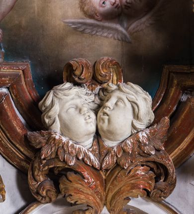 Zdjęcie nr 9: Ołtarz architektoniczny, jednokondygnacyjny, jednoosiowy, ze zwieńczeniem. Ołtarz prostopadłościenny, murowany. Retabulum o strukturze wklęsłej wzdłuż osi pionowej osadzone na niewysokim, cokole zryzalitowanym w formie pary impostów. Gzyms cokołu pośrodku ma formę półkolistego łuku nadwieszonego. Część środkowa ujęta parą wąskich filarów, licami zwróconych ukośnie na zewnątrz, wspierających wydatny gzyms osadzony na parze spływów wolutowych. Pola cokołu retabulum zdobione ornamentyką roślinną. Na impostach para figur aniołków, stojący po lewej stronie w lewej dłoni ma zwój z napisem „PATRZ / SWEGO / A NIE / PRAGNIJ / CUDZEGO”, stojący po prawej trzyma lewą ręką wspartą na podłożu tarczę z napisem „ZLE / NABYTE / NIE / BĘDZIE / DOBRZE / SPOŻYTE”. Między impostami płycina w kształcie prostokąta leżącego o wklęsłych górnych narożach i zamkniętego półkolistym łukiem nadwieszonym. W dolnej partii retabulum para uskrzydlonych główek anielskich dołem ujętych liśćmi akantu. Lica filarów zdobione motywem kampanuli. W partii belkowania, pośrodku motyw akantowego kartusza z napisem „VENI / CORONABE/RIS.”, ujętego górą, dołem i po bokach motywami uskrzydlonych główek anielskich. Zwieńczenie w formie promienistej glorii z koroną osadzoną na obłokach. Całość flankuje para siedzących na gzymsie aniołów w dynamicznych pozach. Pole części środkowej w kształcie stojącego prostokąta ujętego górą i dołem parą zwróconych do siebie półkolistych łuków nadwieszonych z uskokami, ujęte profilowaną, złoconą ramą. Wewnątrz obraz z wizerunkiem Matki Boskiej. Struktura polichromowana w kolorze białym, detal architektoniczny i ornamentyka złocone i srebrzone.