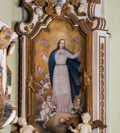 Zdjęcie nr 2: Ołtarz architektoniczny, jednokondygnacyjny, jednoosiowy, ze zwieńczeniem. Ołtarz prostopadłościenny, murowany. Retabulum o strukturze wklęsłej wzdłuż osi pionowej osadzone na niewysokim, cokole zryzalitowanym w formie pary impostów. Gzyms cokołu pośrodku ma formę półkolistego łuku nadwieszonego. Część środkowa ujęta parą wąskich filarów, licami zwróconych ukośnie na zewnątrz, wspierających wydatny gzyms osadzony na parze spływów wolutowych. Pola cokołu retabulum zdobione ornamentyką roślinną. Na impostach para figur aniołków, stojący po lewej stronie w lewej dłoni ma zwój z napisem „PATRZ / SWEGO / A NIE / PRAGNIJ / CUDZEGO”, stojący po prawej trzyma lewą ręką wspartą na podłożu tarczę z napisem „ZLE / NABYTE / NIE / BĘDZIE / DOBRZE / SPOŻYTE”. Między impostami płycina w kształcie prostokąta leżącego o wklęsłych górnych narożach i zamkniętego półkolistym łukiem nadwieszonym. W dolnej partii retabulum para uskrzydlonych główek anielskich dołem ujętych liśćmi akantu. Lica filarów zdobione motywem kampanuli. W partii belkowania, pośrodku motyw akantowego kartusza z napisem „VENI / CORONABE/RIS.”, ujętego górą, dołem i po bokach motywami uskrzydlonych główek anielskich. Zwieńczenie w formie promienistej glorii z koroną osadzoną na obłokach. Całość flankuje para siedzących na gzymsie aniołów w dynamicznych pozach. Pole części środkowej w kształcie stojącego prostokąta ujętego górą i dołem parą zwróconych do siebie półkolistych łuków nadwieszonych z uskokami, ujęte profilowaną, złoconą ramą. Wewnątrz obraz z wizerunkiem Matki Boskiej. Struktura polichromowana w kolorze białym, detal architektoniczny i ornamentyka złocone i srebrzone.