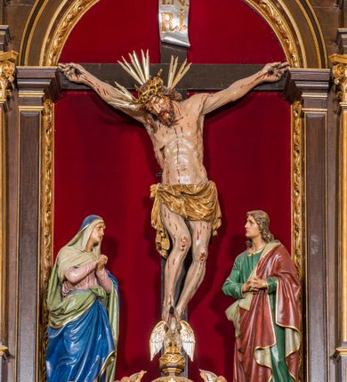 Zdjęcie nr 31: Ołtarz drewniany, architektoniczny, trójosiowy, jednokondygnacyjny ze zwieńczeniem usytuowany w połowie prezbiterium, na całej jego szerokości. Ołtarz prostopadłościenny z drewnianą mensą. Tabernakulum jest trójosiowe, osadzone na podwójnym cokole, zryzalitowane w części środkowej, podzielone kompozytowymi kolumnami, podtrzymującymi wyłamujące się nad nimi belkowanie z przerwanym przyczółkiem pośrodku. W części środkowej ruchomy tron wystawienia, wieloboczny, z rytymi literami IHS na tle glorii promienistej w jednej części i gałązkami z kwiatami w drugiej. Retabulum osadzone na wysokim cokole, z bramkami po bokach zamkniętymi łukami dwuramiennymi. Na dwiczkach malowane wizerunki św. Piotra po prawej i św. Pawła po lewej stronie. Część środkową retabulum ujmują dwie pary kompozytowych pilastrów o kanelowanych trzonech, z których środkowe cofnięte, podtrzymują przełamujące się nad nimi belkowanie i przerwany przyczółek. Zwieńczenie jest ujęte kanelowanymi pilastrami kompozytowymi z naczółkami oraz para ażurowych, ornamentacyjnych uszaków. W części środkowej jest wnęka w kształcie pionowego prostokąta zamkniętego łukiem półkolistym z rzeźbiarską grupą Ukrzyżowania z Matką Boską i św. Janem. W zwieńczeniu jest obraz „Pietas Domini" w sześciobocznej ramie. W osiach bocznych nastawy znajdują się ażurowe arkady z malowanymi wizerunkami Chrystusa u słupa i Ecce Homo. Osie zwieńczone są półkolistymi przyczółkami. W osiach bocznych przeszklone galoty z kompozycją wykonaną z tkanin oraz srebrnych i złotych nici. Dekorację ornamentalną ołtarza i tabernakulum stanowią liście akantu, girlandy i rozety. Struktura utrzymana jest w kolorze brązowym, ornamentyka i detal architektoniczy są złocone. 