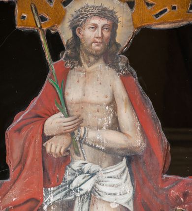 Zdjęcie nr 14: Ołtarz drewniany, architektoniczny, trójosiowy, jednokondygnacyjny ze zwieńczeniem usytuowany w połowie prezbiterium, na całej jego szerokości. Ołtarz prostopadłościenny z drewnianą mensą. Tabernakulum jest trójosiowe, osadzone na podwójnym cokole, zryzalitowane w części środkowej, podzielone kompozytowymi kolumnami, podtrzymującymi wyłamujące się nad nimi belkowanie z przerwanym przyczółkiem pośrodku. W części środkowej ruchomy tron wystawienia, wieloboczny, z rytymi literami IHS na tle glorii promienistej w jednej części i gałązkami z kwiatami w drugiej. Retabulum osadzone na wysokim cokole, z bramkami po bokach zamkniętymi łukami dwuramiennymi. Na dwiczkach malowane wizerunki św. Piotra po prawej i św. Pawła po lewej stronie. Część środkową retabulum ujmują dwie pary kompozytowych pilastrów o kanelowanych trzonech, z których środkowe cofnięte, podtrzymują przełamujące się nad nimi belkowanie i przerwany przyczółek. Zwieńczenie jest ujęte kanelowanymi pilastrami kompozytowymi z naczółkami oraz para ażurowych, ornamentacyjnych uszaków. W części środkowej jest wnęka w kształcie pionowego prostokąta zamkniętego łukiem półkolistym z rzeźbiarską grupą Ukrzyżowania z Matką Boską i św. Janem. W zwieńczeniu jest obraz „Pietas Domini&quot; w sześciobocznej ramie. W osiach bocznych nastawy znajdują się ażurowe arkady z malowanymi wizerunkami Chrystusa u słupa i Ecce Homo. Osie zwieńczone są półkolistymi przyczółkami. W osiach bocznych przeszklone galoty z kompozycją wykonaną z tkanin oraz srebrnych i złotych nici. Dekorację ornamentalną ołtarza i tabernakulum stanowią liście akantu, girlandy i rozety. Struktura utrzymana jest w kolorze brązowym, ornamentyka i detal architektoniczy są złocone. 