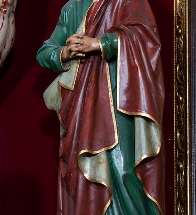 Zdjęcie nr 15: Ołtarz drewniany, architektoniczny, trójosiowy, jednokondygnacyjny ze zwieńczeniem usytuowany w połowie prezbiterium, na całej jego szerokości. Ołtarz prostopadłościenny z drewnianą mensą. Tabernakulum jest trójosiowe, osadzone na podwójnym cokole, zryzalitowane w części środkowej, podzielone kompozytowymi kolumnami, podtrzymującymi wyłamujące się nad nimi belkowanie z przerwanym przyczółkiem pośrodku. W części środkowej ruchomy tron wystawienia, wieloboczny, z rytymi literami IHS na tle glorii promienistej w jednej części i gałązkami z kwiatami w drugiej. Retabulum osadzone na wysokim cokole, z bramkami po bokach zamkniętymi łukami dwuramiennymi. Na dwiczkach malowane wizerunki św. Piotra po prawej i św. Pawła po lewej stronie. Część środkową retabulum ujmują dwie pary kompozytowych pilastrów o kanelowanych trzonech, z których środkowe cofnięte, podtrzymują przełamujące się nad nimi belkowanie i przerwany przyczółek. Zwieńczenie jest ujęte kanelowanymi pilastrami kompozytowymi z naczółkami oraz para ażurowych, ornamentacyjnych uszaków. W części środkowej jest wnęka w kształcie pionowego prostokąta zamkniętego łukiem półkolistym z rzeźbiarską grupą Ukrzyżowania z Matką Boską i św. Janem. W zwieńczeniu jest obraz „Pietas Domini" w sześciobocznej ramie. W osiach bocznych nastawy znajdują się ażurowe arkady z malowanymi wizerunkami Chrystusa u słupa i Ecce Homo. Osie zwieńczone są półkolistymi przyczółkami. W osiach bocznych przeszklone galoty z kompozycją wykonaną z tkanin oraz srebrnych i złotych nici. Dekorację ornamentalną ołtarza i tabernakulum stanowią liście akantu, girlandy i rozety. Struktura utrzymana jest w kolorze brązowym, ornamentyka i detal architektoniczy są złocone. 