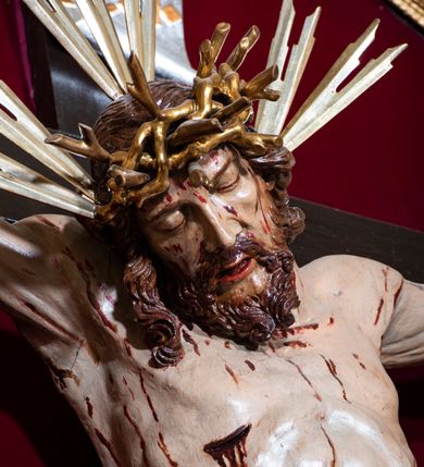 Zdjęcie nr 17: Ołtarz drewniany, architektoniczny, trójosiowy, jednokondygnacyjny ze zwieńczeniem usytuowany w połowie prezbiterium, na całej jego szerokości. Ołtarz prostopadłościenny z drewnianą mensą. Tabernakulum jest trójosiowe, osadzone na podwójnym cokole, zryzalitowane w części środkowej, podzielone kompozytowymi kolumnami, podtrzymującymi wyłamujące się nad nimi belkowanie z przerwanym przyczółkiem pośrodku. W części środkowej ruchomy tron wystawienia, wieloboczny, z rytymi literami IHS na tle glorii promienistej w jednej części i gałązkami z kwiatami w drugiej. Retabulum osadzone na wysokim cokole, z bramkami po bokach zamkniętymi łukami dwuramiennymi. Na dwiczkach malowane wizerunki św. Piotra po prawej i św. Pawła po lewej stronie. Część środkową retabulum ujmują dwie pary kompozytowych pilastrów o kanelowanych trzonech, z których środkowe cofnięte, podtrzymują przełamujące się nad nimi belkowanie i przerwany przyczółek. Zwieńczenie jest ujęte kanelowanymi pilastrami kompozytowymi z naczółkami oraz para ażurowych, ornamentacyjnych uszaków. W części środkowej jest wnęka w kształcie pionowego prostokąta zamkniętego łukiem półkolistym z rzeźbiarską grupą Ukrzyżowania z Matką Boską i św. Janem. W zwieńczeniu jest obraz „Pietas Domini" w sześciobocznej ramie. W osiach bocznych nastawy znajdują się ażurowe arkady z malowanymi wizerunkami Chrystusa u słupa i Ecce Homo. Osie zwieńczone są półkolistymi przyczółkami. W osiach bocznych przeszklone galoty z kompozycją wykonaną z tkanin oraz srebrnych i złotych nici. Dekorację ornamentalną ołtarza i tabernakulum stanowią liście akantu, girlandy i rozety. Struktura utrzymana jest w kolorze brązowym, ornamentyka i detal architektoniczy są złocone. 