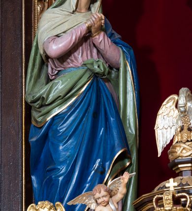 Zdjęcie nr 19: Ołtarz drewniany, architektoniczny, trójosiowy, jednokondygnacyjny ze zwieńczeniem usytuowany w połowie prezbiterium, na całej jego szerokości. Ołtarz prostopadłościenny z drewnianą mensą. Tabernakulum jest trójosiowe, osadzone na podwójnym cokole, zryzalitowane w części środkowej, podzielone kompozytowymi kolumnami, podtrzymującymi wyłamujące się nad nimi belkowanie z przerwanym przyczółkiem pośrodku. W części środkowej ruchomy tron wystawienia, wieloboczny, z rytymi literami IHS na tle glorii promienistej w jednej części i gałązkami z kwiatami w drugiej. Retabulum osadzone na wysokim cokole, z bramkami po bokach zamkniętymi łukami dwuramiennymi. Na dwiczkach malowane wizerunki św. Piotra po prawej i św. Pawła po lewej stronie. Część środkową retabulum ujmują dwie pary kompozytowych pilastrów o kanelowanych trzonech, z których środkowe cofnięte, podtrzymują przełamujące się nad nimi belkowanie i przerwany przyczółek. Zwieńczenie jest ujęte kanelowanymi pilastrami kompozytowymi z naczółkami oraz para ażurowych, ornamentacyjnych uszaków. W części środkowej jest wnęka w kształcie pionowego prostokąta zamkniętego łukiem półkolistym z rzeźbiarską grupą Ukrzyżowania z Matką Boską i św. Janem. W zwieńczeniu jest obraz „Pietas Domini" w sześciobocznej ramie. W osiach bocznych nastawy znajdują się ażurowe arkady z malowanymi wizerunkami Chrystusa u słupa i Ecce Homo. Osie zwieńczone są półkolistymi przyczółkami. W osiach bocznych przeszklone galoty z kompozycją wykonaną z tkanin oraz srebrnych i złotych nici. Dekorację ornamentalną ołtarza i tabernakulum stanowią liście akantu, girlandy i rozety. Struktura utrzymana jest w kolorze brązowym, ornamentyka i detal architektoniczy są złocone. 