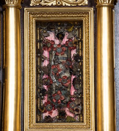 Zdjęcie nr 18: Ołtarz drewniany, architektoniczny, trójosiowy, jednokondygnacyjny ze zwieńczeniem usytuowany w połowie prezbiterium, na całej jego szerokości. Ołtarz prostopadłościenny z drewnianą mensą. Tabernakulum jest trójosiowe, osadzone na podwójnym cokole, zryzalitowane w części środkowej, podzielone kompozytowymi kolumnami, podtrzymującymi wyłamujące się nad nimi belkowanie z przerwanym przyczółkiem pośrodku. W części środkowej ruchomy tron wystawienia, wieloboczny, z rytymi literami IHS na tle glorii promienistej w jednej części i gałązkami z kwiatami w drugiej. Retabulum osadzone na wysokim cokole, z bramkami po bokach zamkniętymi łukami dwuramiennymi. Na dwiczkach malowane wizerunki św. Piotra po prawej i św. Pawła po lewej stronie. Część środkową retabulum ujmują dwie pary kompozytowych pilastrów o kanelowanych trzonech, z których środkowe cofnięte, podtrzymują przełamujące się nad nimi belkowanie i przerwany przyczółek. Zwieńczenie jest ujęte kanelowanymi pilastrami kompozytowymi z naczółkami oraz para ażurowych, ornamentacyjnych uszaków. W części środkowej jest wnęka w kształcie pionowego prostokąta zamkniętego łukiem półkolistym z rzeźbiarską grupą Ukrzyżowania z Matką Boską i św. Janem. W zwieńczeniu jest obraz „Pietas Domini" w sześciobocznej ramie. W osiach bocznych nastawy znajdują się ażurowe arkady z malowanymi wizerunkami Chrystusa u słupa i Ecce Homo. Osie zwieńczone są półkolistymi przyczółkami. W osiach bocznych przeszklone galoty z kompozycją wykonaną z tkanin oraz srebrnych i złotych nici. Dekorację ornamentalną ołtarza i tabernakulum stanowią liście akantu, girlandy i rozety. Struktura utrzymana jest w kolorze brązowym, ornamentyka i detal architektoniczy są złocone. 