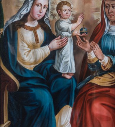 Zdjęcie nr 3: Obraz w kształcie stojącego prostokąta z przedstawieniem św. Anny Samotrzeć. Lewą stronę kompozycji zajmuje zwrócona w trzech czwartych w lewo Maria, siedząca na drewnianym fotelu z rzeźbionymi podłokietnikami. Owalną twarz charakteryzują pełne, sumarycznie opracowane rysy młodej kobiety i wzrok skierowany w stronę widza. Spod osłaniającej głowę białej chusty widoczne są długie, falowane, ciemnobrązowe włosy. Maria ubrana jest w kremową suknię ze złoconym obszyciem dekoltu. Na ramiona narzucony ma ciemnoniebieski płaszcz osłaniający nogi, na stopach są sandały, na głowie otwarta korona. Maria oburącz podtrzymuje stojące na jej lewym kolanie Dzieciątko Jezus zwrócone profilem w lewo. Głowa, o zaokrąglonej twarzy i pełnych rysach, skierowana jest w trzech czwartych w prawo. Ubrany w długą, białą suknię Jezus prawą rękę unosi w geście błogosławieństwa, w lewej trzyma kulę ziemskiego globu zwieńczoną krzyżem.     
Po prawej stronie kompozycji ukazana jest siedząca na krześle w typie faldistorium, nakrytym zieloną poduszką, św. Anna w trzech czwartych zwrócona w prawo. Owalną twarz charakteryzują wyraziste, plastycznie opracowane rysy. Święta ubrana jest w spodnią białą i wierzchnią niebieską suknię. Głowę osłania biała chusta z podwiką widoczna spod długiego, czerwonego płaszcza z żółtym podszyciem, osłaniającego także ramiona, plecy i nogi. Lekko uniesione, zgięte w łokciach ręce wyciąga przed siebie w prawo, w kierunku Dzieciątka Jezus. Głowy Marii, Jezusa i św. Anny ujmują promieniste nimby. Postaci ukazane są we wnętrzu otwierającym się na pokryte obłokami niebo. Posadzkę tworzy szachownicowy układ biało-bordowych, kwadratowych płytek, fotel Marii usytuowany jest na niskim podeście. Na pierwszym planie, po prawej stronie leży kosz z owocami: gruszką, winogronami i jabłkiem. W górnej partii kompozycję ujmuje dekoracyjnie podpięta, ciemnozielona kotara.  
