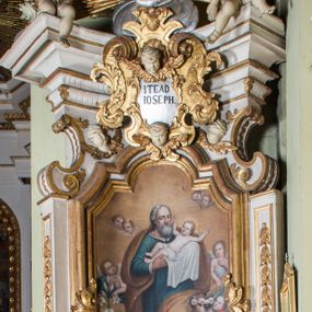 Zdjęcie nr 1: Ołtarz architektoniczny, jednokondygnacyjny, jednoosiowy, ze zwieńczeniem. Ołtarz prostopadłościenny, murowany. Retabulum o strukturze wklęsłej wzdłuż osi pionowej osadzone na niewysokim, cokole zryzalitowanym w formie pary impostów. Gzyms cokołu pośrodku ma formę półkolistego łuku nadwieszonego. Część środkowa ujęta parą wąskich filarów, licami zwróconych ukośnie w prawo, wspierających wydatny gzyms osadzony na parze spływów wolutowych. Pola cokołu retabulum zdobione ornamentyką roślinną. Na impostach para figur aniołków, stojący po lewej stronie trzyma w dłoniach zwój z napisem „KOCHAJ BOGA / I BLIZNIEGO”, stojący po prawej lewą rękę wspiera na kartuszu z napisem „POZNAJ / SIEBIE / SAMEGO”. Miedzy impostami płycina w kształcie prostokąta leżącego o wklęsłych górnych narożach i zamkniętego półkolistym łukiem nadwieszonym. W dolnej partii retabulum para uskrzydlonych główek anielskich dołem ujętych liśćmi akantu. Lica filarów zdobione motywem kampanuli. W partii belkowania, pośrodku motyw akantowego kartusza z napisem „ITE AD / IOSEPH.”, ujętego górą, dołem i po bokach motywami uskrzydlonych główek anielskich. Zwieńczenie w formie promienistej glorii z koroną zdobioną kwiatami osadzoną na obłokach. Całość flankuje para siedzących na gzymsie aniołów w dynamicznych pozach. Pole części środkowej w kształcie stojącego prostokąta ujętego górą i dołem parą zwróconych do siebie półkolistych łuków nadwieszonych z uskokami, ujęte profilowaną, złoconą ramą. Wewnątrz obraz z wizerunkiem św. Józefa. Struktura polichromowana w kolorze białym, detal architektoniczny i ornamentyka złocone i srebrzone.