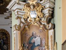 Zdjęcie nr 1: Ołtarz architektoniczny, jednokondygnacyjny, jednoosiowy, ze zwieńczeniem. Ołtarz prostopadłościenny, murowany. Retabulum o strukturze wklęsłej wzdłuż osi pionowej osadzone na niewysokim, cokole zryzalitowanym w formie pary impostów. Gzyms cokołu pośrodku ma formę półkolistego łuku nadwieszonego. Część środkowa ujęta parą wąskich filarów, licami zwróconych ukośnie w prawo, wspierających wydatny gzyms osadzony na parze spływów wolutowych. Pola cokołu retabulum zdobione ornamentyką roślinną. Na impostach para figur aniołków, stojący po lewej stronie trzyma w dłoniach zwój z napisem „KOCHAJ BOGA / I BLIZNIEGO”, stojący po prawej lewą rękę wspiera na kartuszu z napisem „POZNAJ / SIEBIE / SAMEGO”. Miedzy impostami płycina w kształcie prostokąta leżącego o wklęsłych górnych narożach i zamkniętego półkolistym łukiem nadwieszonym. W dolnej partii retabulum para uskrzydlonych główek anielskich dołem ujętych liśćmi akantu. Lica filarów zdobione motywem kampanuli. W partii belkowania, pośrodku motyw akantowego kartusza z napisem „ITE AD / IOSEPH.”, ujętego górą, dołem i po bokach motywami uskrzydlonych główek anielskich. Zwieńczenie w formie promienistej glorii z koroną zdobioną kwiatami osadzoną na obłokach. Całość flankuje para siedzących na gzymsie aniołów w dynamicznych pozach. Pole części środkowej w kształcie stojącego prostokąta ujętego górą i dołem parą zwróconych do siebie półkolistych łuków nadwieszonych z uskokami, ujęte profilowaną, złoconą ramą. Wewnątrz obraz z wizerunkiem św. Józefa. Struktura polichromowana w kolorze białym, detal architektoniczny i ornamentyka złocone i srebrzone.