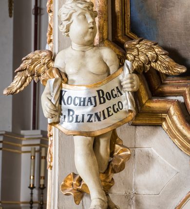 Zdjęcie nr 8: Ołtarz architektoniczny, jednokondygnacyjny, jednoosiowy, ze zwieńczeniem. Ołtarz prostopadłościenny, murowany. Retabulum o strukturze wklęsłej wzdłuż osi pionowej osadzone na niewysokim, cokole zryzalitowanym w formie pary impostów. Gzyms cokołu pośrodku ma formę półkolistego łuku nadwieszonego. Część środkowa ujęta parą wąskich filarów, licami zwróconych ukośnie w prawo, wspierających wydatny gzyms osadzony na parze spływów wolutowych. Pola cokołu retabulum zdobione ornamentyką roślinną. Na impostach para figur aniołków, stojący po lewej stronie trzyma w dłoniach zwój z napisem „KOCHAJ BOGA / I BLIZNIEGO”, stojący po prawej lewą rękę wspiera na kartuszu z napisem „POZNAJ / SIEBIE / SAMEGO”. Miedzy impostami płycina w kształcie prostokąta leżącego o wklęsłych górnych narożach i zamkniętego półkolistym łukiem nadwieszonym. W dolnej partii retabulum para uskrzydlonych główek anielskich dołem ujętych liśćmi akantu. Lica filarów zdobione motywem kampanuli. W partii belkowania, pośrodku motyw akantowego kartusza z napisem „ITE AD / IOSEPH.”, ujętego górą, dołem i po bokach motywami uskrzydlonych główek anielskich. Zwieńczenie w formie promienistej glorii z koroną zdobioną kwiatami osadzoną na obłokach. Całość flankuje para siedzących na gzymsie aniołów w dynamicznych pozach. Pole części środkowej w kształcie stojącego prostokąta ujętego górą i dołem parą zwróconych do siebie półkolistych łuków nadwieszonych z uskokami, ujęte profilowaną, złoconą ramą. Wewnątrz obraz z wizerunkiem św. Józefa. Struktura polichromowana w kolorze białym, detal architektoniczny i ornamentyka złocone i srebrzone.