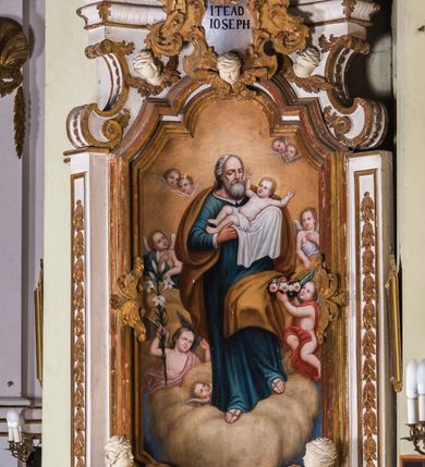 Zdjęcie nr 11: Ołtarz architektoniczny, jednokondygnacyjny, jednoosiowy, ze zwieńczeniem. Ołtarz prostopadłościenny, murowany. Retabulum o strukturze wklęsłej wzdłuż osi pionowej osadzone na niewysokim, cokole zryzalitowanym w formie pary impostów. Gzyms cokołu pośrodku ma formę półkolistego łuku nadwieszonego. Część środkowa ujęta parą wąskich filarów, licami zwróconych ukośnie w prawo, wspierających wydatny gzyms osadzony na parze spływów wolutowych. Pola cokołu retabulum zdobione ornamentyką roślinną. Na impostach para figur aniołków, stojący po lewej stronie trzyma w dłoniach zwój z napisem „KOCHAJ BOGA / I BLIZNIEGO”, stojący po prawej lewą rękę wspiera na kartuszu z napisem „POZNAJ / SIEBIE / SAMEGO”. Miedzy impostami płycina w kształcie prostokąta leżącego o wklęsłych górnych narożach i zamkniętego półkolistym łukiem nadwieszonym. W dolnej partii retabulum para uskrzydlonych główek anielskich dołem ujętych liśćmi akantu. Lica filarów zdobione motywem kampanuli. W partii belkowania, pośrodku motyw akantowego kartusza z napisem „ITE AD / IOSEPH.”, ujętego górą, dołem i po bokach motywami uskrzydlonych główek anielskich. Zwieńczenie w formie promienistej glorii z koroną zdobioną kwiatami osadzoną na obłokach. Całość flankuje para siedzących na gzymsie aniołów w dynamicznych pozach. Pole części środkowej w kształcie stojącego prostokąta ujętego górą i dołem parą zwróconych do siebie półkolistych łuków nadwieszonych z uskokami, ujęte profilowaną, złoconą ramą. Wewnątrz obraz z wizerunkiem św. Józefa. Struktura polichromowana w kolorze białym, detal architektoniczny i ornamentyka złocone i srebrzone.