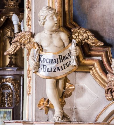 Zdjęcie nr 7: Ołtarz architektoniczny, jednokondygnacyjny, jednoosiowy, ze zwieńczeniem. Ołtarz prostopadłościenny, murowany. Retabulum o strukturze wklęsłej wzdłuż osi pionowej osadzone na niewysokim, cokole zryzalitowanym w formie pary impostów. Gzyms cokołu pośrodku ma formę półkolistego łuku nadwieszonego. Część środkowa ujęta parą wąskich filarów, licami zwróconych ukośnie w prawo, wspierających wydatny gzyms osadzony na parze spływów wolutowych. Pola cokołu retabulum zdobione ornamentyką roślinną. Na impostach para figur aniołków, stojący po lewej stronie trzyma w dłoniach zwój z napisem „KOCHAJ BOGA / I BLIZNIEGO”, stojący po prawej lewą rękę wspiera na kartuszu z napisem „POZNAJ / SIEBIE / SAMEGO”. Miedzy impostami płycina w kształcie prostokąta leżącego o wklęsłych górnych narożach i zamkniętego półkolistym łukiem nadwieszonym. W dolnej partii retabulum para uskrzydlonych główek anielskich dołem ujętych liśćmi akantu. Lica filarów zdobione motywem kampanuli. W partii belkowania, pośrodku motyw akantowego kartusza z napisem „ITE AD / IOSEPH.”, ujętego górą, dołem i po bokach motywami uskrzydlonych główek anielskich. Zwieńczenie w formie promienistej glorii z koroną zdobioną kwiatami osadzoną na obłokach. Całość flankuje para siedzących na gzymsie aniołów w dynamicznych pozach. Pole części środkowej w kształcie stojącego prostokąta ujętego górą i dołem parą zwróconych do siebie półkolistych łuków nadwieszonych z uskokami, ujęte profilowaną, złoconą ramą. Wewnątrz obraz z wizerunkiem św. Józefa. Struktura polichromowana w kolorze białym, detal architektoniczny i ornamentyka złocone i srebrzone.
