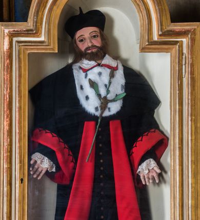 Zdjęcie nr 1: Całopostaciowa, pełnoplastyczna figura św. Jana Kantego ukazanego w pozycji stojącej i zwróconego na wprost. Lekko przechyloną na prawe ramię głowę charakteryzuje szeroka, owalna twarz o sumarycznie opracowanych wyrazistych rysach z dużymi, ciemnymi oczami, dużym nosem, wąskimi ustami oraz krótkim zarostem. Proste, brązowe włosy wspierają się na barkach mężczyzny. Święty Jan ubrany jest w czarną togę profesora akademickiego z szerokimi, czerwonymi obszyciami oraz z dużym kołnierzem z futra gronostajowego, na który wyłożony jest biały, obszyty koronką kołnierzyk spodniego ubioru. Na głowie ma biret, a na stopach czarne buty. Opuszczone wzdłuż ciała ręce rozchylone są nieznacznie na boki. Do piersi przytwierdzony jest kwiat lilii z figurą Jezusa ukrzyżowanego. 
Gablota, w której umieszczona jest figura św. Jana Kantego, ma formę prostopadłościennej szafki. Przeszklone drzwiczki, w kształcie stojącego prostokąta zamkniętego półkolistym łukiem nadwieszonym, ujęte są profilowanym, złoconym obramieniem.  
