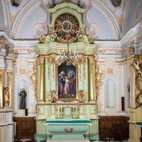 Zdjęcie nr 1: Ołtarz architektoniczny, jednokondygnacyjny, jednoosiowy, ze zwieńczeniem. Ołtarz sarkofagowy, z drewnianą mensą, pośrodku pola antepedium polichromowany monogram maryjny ujęty parą gałązek różanych. Tabernakulum w formie prostopadłościennej szafki osadzonej na zdwojonym cokole, o narożach ujętych parą skośnie ustawionych pilastrów wspierających wyłamujący się ponad nimi gzyms wieńczący, w części środkowej przybierający formę dwóch stykających się wolut. Drzwiczki są w kształcie stojącego prostokąta zamkniętego łukiem półkolistym, ujęte profilowaną, złoconą ramą. W polu płaskorzeźbiony motyw kielicha eucharystycznego. Retabulum osadzone na wysokim, zdwojonym cokole. Część środkowa ujęta parą filarów i parą cofniętych kolumn o kapitelach korynckich. Podpory wspierają wyłamujące się ponad nimi belkowanie z wydatnym gzymsem. Zwieńczenie w formie trapezoidalnej ujęte parą spływów wolutowych, zamknięte fragmentem gzymsu w postaci nawieszonego łuku odcinkowego z uskokami, dodatkowo flankowane przerwanym przyczółkiem wolutowym. Dolny cokół retabulum zdobiony motywami kogucich grzebieni, pola górnego artykułowane fragmentami ornamentu roślinnego, całość ujęta małymi uszakami skomponowanymi z kogucich grzebieni. Trzony filarów dołem zdobione rocaille’owymi kartuszami, górą podwieszenia rocaille’owe. Fryz zdobiony motywami ornamentyki roślinnej. Retabulum ujęte parą ażurowych uszaków skomponowanych z wici roślinnej i kogucich grzebieni. W zwieńczeniu, pośrodku wsparta na belkowaniu duża korona, na przerwanym przyczółku para aniołków z ulistnionymi gałązkami w podniesionych rękach. Gzyms wieńczący ujęty dołem rodzajem lambrekinu z pojedynczych liści akantu. Szczyt w formie ażurowego kartusza rocaille’owego ujęty po bokach parą płomienistych wazonów. Pole części środkowej w kształcie stojącego prostokąta zamkniętego półkolistym łukiem nawieszonym z uskokami, ujęte profilowaną, złoconą ramą. W środku obraz „Święta Rodzina” („Znalezienie Jezusa w świątyni”), na cokole retabulum para figur, po lewej św. Michał Archanioł, po prawej św. Rafał Archanioł. Pole zwieńczenia w postaci otworu w kształcie stojącego owalu wypełnione ażurową, promienistą glorią z monogramem maryjnym pośrodku ujętym wieńcem obłoków. Struktura polichromowana w odcieniu jasnej zieleni, detal architektoniczny i ornamentyka polichromowane w kolorze bordowym, złocone i srebrzone. 