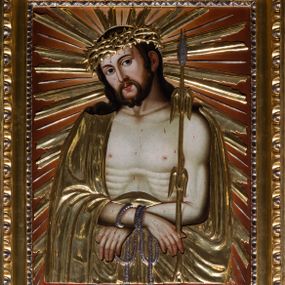 Zdjęcie nr 1: Obraz uzyskał kształt stojącego prostokąta ujętego złoconą, profilowaną ramą z dekoracją w typie wolich oczu. W centrum kompozycji ukazano frontalnie w dwóch trzecich Chrystusa z nieznacznie pochyloną głową w prawo ujętą w trzech czwartych.  Zbawiciel ma skrzyżowane z przodu i związane sznurem ręce. W prawej dłoni trzyma trzcinę. Ma pociągłą twarz o jasnej karnacji okoloną krótką brodą i brązowymi włosami spływającymi na ramiona. Jezus ma duży, prosty nos, wydatne usta i szeroko otwarte ciemne oczy. Na głowie ma złoconą koronę cierniową, spod której spływają krople krwi. Jego głowę otaczają ostre, złocone promienie. Krew widoczna jest także na odsłoniętym torsie oraz rękach. Chrystus ubrany jest w płaszcz narzucony na ramiona odsłaniający jego nagi tors. Zarówno płaszcz, jak i korona cierniowa, trzcina oraz sznur zostały przykryte płaskorzeźbioną, drewnianą sukienką wotywną. 