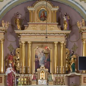Zdjęcie nr 1: Jednokondygnacyjna nastawa ze zwieńczeniem uzyskała architektoniczną strukturę wzbogaconą o  flankujące ją bramkami. Współczesny marmurowy stipes ołtarzowy wspierający mensę uzyskał formę prostopadłościanu z licem artykułowanym dwiema półkolumienkami. Na mensie ustawiono tabernakulum w formie drewnianej skrzynki, obitej trybowaną blachą. Drzwiczki uzyskały kształt stojącego prostokąta zamkniętego łukiem półkolistym. W ich polu wyobrażono kielich z hostią w glorii, ujęty trybowanym winnym gronem i aplikowanymi kłosami zbóż. Z dwóch stron drzwiczek widnieje trybowana dekoracja w postaci winnego grona. Na tabernakulum usytuowano tron wystawienia, w postaci obrotowej niszy ujętej dwiema parami kolumienek podtrzymujących gzyms wyłamany pośrodku na kształt łuku odcinkowego oraz cokół z figurką baranka na księdze z siedmioma pieczęciami, podtrzymywany przez dwa spływy wolutowe. Tabernakulum ujęte zostało dwoma postumentami dekorowanymi z przodu rozetami. Ustawiono na nich figury klęczących aniołów. Nastawa ujęta została dwiema parami kolumn o kapitelach kompozytowych ustawionych na cokołach dekorowanych płycinami z ornamentem roślinnym, podtrzymujących pełne belkowanie z silnie wysuniętym gzymsem, oraz zewnętrzną parą cofniętych w tył kolumn. W polu głównym usytuowano obraz z przedstawieniem Zmartwychwstałego Chrystusa ze św. Janem Chrzcicielem i św. Janem Ewangelistą, ujęty profilowaną ramą w formie stojącego prostokąta zamkniętego łukiem odcinkowych nadwieszonym. Kondygnacja ujęta została po bokach uszami utworzonymi z karbowanej wstęgi i akantu. Zwieńczenie nastawy ustawiono na schodkowym, zwężającym się cokole, dekorowanym medalionem z monogramem Marii oraz anthemionami. Ujmują je dwie pary kolumienek o kapitelach kompozytowych podtrzymujących gzyms wyłamujący się po środku na kształt łuku półkolistego, dekorowany wicią roślinną. W polu zwieńczenia znalazł się obraz w formie stojącego owalu z przedstawieniem Dzieciątka Jezus prezentującego krzyż, ujęty profilowaną ramą dekorowaną ornamentem roślinnym. Zwieńczenie flankują stojące na gzymsie figury św. Józefa z Dzieciątkiem i Symeona z Dzieciątkiem. Nastawę flankują znajdujące się przy ścianie para kolumn i para półkolumn ustawionych na dwustrefowych cokołach, dźwigających pełne belkowanie, na którym siedzą dwa putta. Pomiędzy cokołem nastawy i zewnętrznych podpór ulokowano wygięte listwy tworzące bramki, na których stoją figury św. Piotra i św. Pawła. Struktura retabulum jest polichromowana w kolorze beżowym, z białymi i czerwonymi profilami i płycinami. Kolumny, ornamentyka i profile zostały pozłocone.