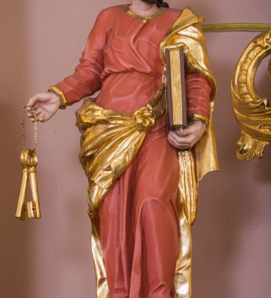 Zdjęcie nr 10: Jednokondygnacyjna nastawa ze zwieńczeniem uzyskała architektoniczną strukturę wzbogaconą o  flankujące ją bramkami. Współczesny marmurowy stipes ołtarzowy wspierający mensę uzyskał formę prostopadłościanu z licem artykułowanym dwiema półkolumienkami. Na mensie ustawiono tabernakulum w formie drewnianej skrzynki, obitej trybowaną blachą. Drzwiczki uzyskały kształt stojącego prostokąta zamkniętego łukiem półkolistym. W ich polu wyobrażono kielich z hostią w glorii, ujęty trybowanym winnym gronem i aplikowanymi kłosami zbóż. Z dwóch stron drzwiczek widnieje trybowana dekoracja w postaci winnego grona. Na tabernakulum usytuowano tron wystawienia, w postaci obrotowej niszy ujętej dwiema parami kolumienek podtrzymujących gzyms wyłamany pośrodku na kształt łuku odcinkowego oraz cokół z figurką baranka na księdze z siedmioma pieczęciami, podtrzymywany przez dwa spływy wolutowe. Tabernakulum ujęte zostało dwoma postumentami dekorowanymi z przodu rozetami. Ustawiono na nich figury klęczących aniołów. Nastawa ujęta została dwiema parami kolumn o kapitelach kompozytowych ustawionych na cokołach dekorowanych płycinami z ornamentem roślinnym, podtrzymujących pełne belkowanie z silnie wysuniętym gzymsem, oraz zewnętrzną parą cofniętych w tył kolumn. W polu głównym usytuowano obraz z przedstawieniem Zmartwychwstałego Chrystusa ze św. Janem Chrzcicielem i św. Janem Ewangelistą, ujęty profilowaną ramą w formie stojącego prostokąta zamkniętego łukiem odcinkowych nadwieszonym. Kondygnacja ujęta została po bokach uszami utworzonymi z karbowanej wstęgi i akantu. Zwieńczenie nastawy ustawiono na schodkowym, zwężającym się cokole, dekorowanym medalionem z monogramem Marii oraz anthemionami. Ujmują je dwie pary kolumienek o kapitelach kompozytowych podtrzymujących gzyms wyłamujący się po środku na kształt łuku półkolistego, dekorowany wicią roślinną. W polu zwieńczenia znalazł się obraz w formie stojącego owalu z przedstawieniem Dzieciątka Jezus prezentującego krzyż, ujęty profilowaną ramą dekorowaną ornamentem roślinnym. Zwieńczenie flankują stojące na gzymsie figury św. Józefa z Dzieciątkiem i Symeona z Dzieciątkiem. Nastawę flankują znajdujące się przy ścianie para kolumn i para półkolumn ustawionych na dwustrefowych cokołach, dźwigających pełne belkowanie, na którym siedzą dwa putta. Pomiędzy cokołem nastawy i zewnętrznych podpór ulokowano wygięte listwy tworzące bramki, na których stoją figury św. Piotra i św. Pawła. Struktura retabulum jest polichromowana w kolorze beżowym, z białymi i czerwonymi profilami i płycinami. Kolumny, ornamentyka i profile zostały pozłocone.