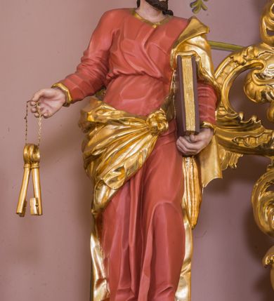 Zdjęcie nr 11: Jednokondygnacyjna nastawa ze zwieńczeniem uzyskała architektoniczną strukturę wzbogaconą o  flankujące ją bramkami. Współczesny marmurowy stipes ołtarzowy wspierający mensę uzyskał formę prostopadłościanu z licem artykułowanym dwiema półkolumienkami. Na mensie ustawiono tabernakulum w formie drewnianej skrzynki, obitej trybowaną blachą. Drzwiczki uzyskały kształt stojącego prostokąta zamkniętego łukiem półkolistym. W ich polu wyobrażono kielich z hostią w glorii, ujęty trybowanym winnym gronem i aplikowanymi kłosami zbóż. Z dwóch stron drzwiczek widnieje trybowana dekoracja w postaci winnego grona. Na tabernakulum usytuowano tron wystawienia, w postaci obrotowej niszy ujętej dwiema parami kolumienek podtrzymujących gzyms wyłamany pośrodku na kształt łuku odcinkowego oraz cokół z figurką baranka na księdze z siedmioma pieczęciami, podtrzymywany przez dwa spływy wolutowe. Tabernakulum ujęte zostało dwoma postumentami dekorowanymi z przodu rozetami. Ustawiono na nich figury klęczących aniołów. Nastawa ujęta została dwiema parami kolumn o kapitelach kompozytowych ustawionych na cokołach dekorowanych płycinami z ornamentem roślinnym, podtrzymujących pełne belkowanie z silnie wysuniętym gzymsem, oraz zewnętrzną parą cofniętych w tył kolumn. W polu głównym usytuowano obraz z przedstawieniem Zmartwychwstałego Chrystusa ze św. Janem Chrzcicielem i św. Janem Ewangelistą, ujęty profilowaną ramą w formie stojącego prostokąta zamkniętego łukiem odcinkowych nadwieszonym. Kondygnacja ujęta została po bokach uszami utworzonymi z karbowanej wstęgi i akantu. Zwieńczenie nastawy ustawiono na schodkowym, zwężającym się cokole, dekorowanym medalionem z monogramem Marii oraz anthemionami. Ujmują je dwie pary kolumienek o kapitelach kompozytowych podtrzymujących gzyms wyłamujący się po środku na kształt łuku półkolistego, dekorowany wicią roślinną. W polu zwieńczenia znalazł się obraz w formie stojącego owalu z przedstawieniem Dzieciątka Jezus prezentującego krzyż, ujęty profilowaną ramą dekorowaną ornamentem roślinnym. Zwieńczenie flankują stojące na gzymsie figury św. Józefa z Dzieciątkiem i Symeona z Dzieciątkiem. Nastawę flankują znajdujące się przy ścianie para kolumn i para półkolumn ustawionych na dwustrefowych cokołach, dźwigających pełne belkowanie, na którym siedzą dwa putta. Pomiędzy cokołem nastawy i zewnętrznych podpór ulokowano wygięte listwy tworzące bramki, na których stoją figury św. Piotra i św. Pawła. Struktura retabulum jest polichromowana w kolorze beżowym, z białymi i czerwonymi profilami i płycinami. Kolumny, ornamentyka i profile zostały pozłocone.