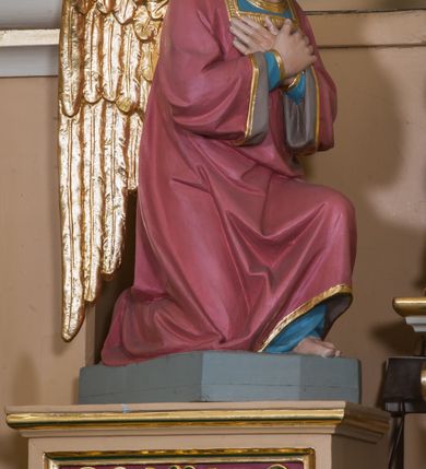 Zdjęcie nr 17: Jednokondygnacyjna nastawa ze zwieńczeniem uzyskała architektoniczną strukturę wzbogaconą o  flankujące ją bramkami. Współczesny marmurowy stipes ołtarzowy wspierający mensę uzyskał formę prostopadłościanu z licem artykułowanym dwiema półkolumienkami. Na mensie ustawiono tabernakulum w formie drewnianej skrzynki, obitej trybowaną blachą. Drzwiczki uzyskały kształt stojącego prostokąta zamkniętego łukiem półkolistym. W ich polu wyobrażono kielich z hostią w glorii, ujęty trybowanym winnym gronem i aplikowanymi kłosami zbóż. Z dwóch stron drzwiczek widnieje trybowana dekoracja w postaci winnego grona. Na tabernakulum usytuowano tron wystawienia, w postaci obrotowej niszy ujętej dwiema parami kolumienek podtrzymujących gzyms wyłamany pośrodku na kształt łuku odcinkowego oraz cokół z figurką baranka na księdze z siedmioma pieczęciami, podtrzymywany przez dwa spływy wolutowe. Tabernakulum ujęte zostało dwoma postumentami dekorowanymi z przodu rozetami. Ustawiono na nich figury klęczących aniołów. Nastawa ujęta została dwiema parami kolumn o kapitelach kompozytowych ustawionych na cokołach dekorowanych płycinami z ornamentem roślinnym, podtrzymujących pełne belkowanie z silnie wysuniętym gzymsem, oraz zewnętrzną parą cofniętych w tył kolumn. W polu głównym usytuowano obraz z przedstawieniem Zmartwychwstałego Chrystusa ze św. Janem Chrzcicielem i św. Janem Ewangelistą, ujęty profilowaną ramą w formie stojącego prostokąta zamkniętego łukiem odcinkowych nadwieszonym. Kondygnacja ujęta została po bokach uszami utworzonymi z karbowanej wstęgi i akantu. Zwieńczenie nastawy ustawiono na schodkowym, zwężającym się cokole, dekorowanym medalionem z monogramem Marii oraz anthemionami. Ujmują je dwie pary kolumienek o kapitelach kompozytowych podtrzymujących gzyms wyłamujący się po środku na kształt łuku półkolistego, dekorowany wicią roślinną. W polu zwieńczenia znalazł się obraz w formie stojącego owalu z przedstawieniem Dzieciątka Jezus prezentującego krzyż, ujęty profilowaną ramą dekorowaną ornamentem roślinnym. Zwieńczenie flankują stojące na gzymsie figury św. Józefa z Dzieciątkiem i Symeona z Dzieciątkiem. Nastawę flankują znajdujące się przy ścianie para kolumn i para półkolumn ustawionych na dwustrefowych cokołach, dźwigających pełne belkowanie, na którym siedzą dwa putta. Pomiędzy cokołem nastawy i zewnętrznych podpór ulokowano wygięte listwy tworzące bramki, na których stoją figury św. Piotra i św. Pawła. Struktura retabulum jest polichromowana w kolorze beżowym, z białymi i czerwonymi profilami i płycinami. Kolumny, ornamentyka i profile zostały pozłocone.