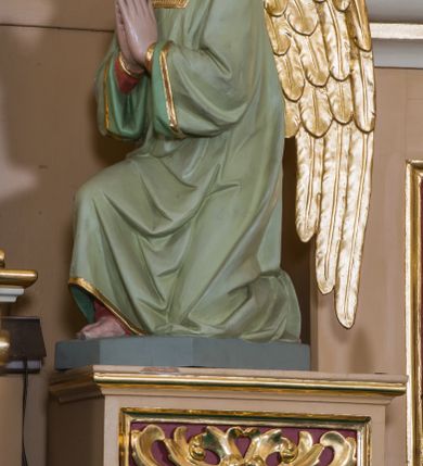 Zdjęcie nr 18: Jednokondygnacyjna nastawa ze zwieńczeniem uzyskała architektoniczną strukturę wzbogaconą o  flankujące ją bramkami. Współczesny marmurowy stipes ołtarzowy wspierający mensę uzyskał formę prostopadłościanu z licem artykułowanym dwiema półkolumienkami. Na mensie ustawiono tabernakulum w formie drewnianej skrzynki, obitej trybowaną blachą. Drzwiczki uzyskały kształt stojącego prostokąta zamkniętego łukiem półkolistym. W ich polu wyobrażono kielich z hostią w glorii, ujęty trybowanym winnym gronem i aplikowanymi kłosami zbóż. Z dwóch stron drzwiczek widnieje trybowana dekoracja w postaci winnego grona. Na tabernakulum usytuowano tron wystawienia, w postaci obrotowej niszy ujętej dwiema parami kolumienek podtrzymujących gzyms wyłamany pośrodku na kształt łuku odcinkowego oraz cokół z figurką baranka na księdze z siedmioma pieczęciami, podtrzymywany przez dwa spływy wolutowe. Tabernakulum ujęte zostało dwoma postumentami dekorowanymi z przodu rozetami. Ustawiono na nich figury klęczących aniołów. Nastawa ujęta została dwiema parami kolumn o kapitelach kompozytowych ustawionych na cokołach dekorowanych płycinami z ornamentem roślinnym, podtrzymujących pełne belkowanie z silnie wysuniętym gzymsem, oraz zewnętrzną parą cofniętych w tył kolumn. W polu głównym usytuowano obraz z przedstawieniem Zmartwychwstałego Chrystusa ze św. Janem Chrzcicielem i św. Janem Ewangelistą, ujęty profilowaną ramą w formie stojącego prostokąta zamkniętego łukiem odcinkowych nadwieszonym. Kondygnacja ujęta została po bokach uszami utworzonymi z karbowanej wstęgi i akantu. Zwieńczenie nastawy ustawiono na schodkowym, zwężającym się cokole, dekorowanym medalionem z monogramem Marii oraz anthemionami. Ujmują je dwie pary kolumienek o kapitelach kompozytowych podtrzymujących gzyms wyłamujący się po środku na kształt łuku półkolistego, dekorowany wicią roślinną. W polu zwieńczenia znalazł się obraz w formie stojącego owalu z przedstawieniem Dzieciątka Jezus prezentującego krzyż, ujęty profilowaną ramą dekorowaną ornamentem roślinnym. Zwieńczenie flankują stojące na gzymsie figury św. Józefa z Dzieciątkiem i Symeona z Dzieciątkiem. Nastawę flankują znajdujące się przy ścianie para kolumn i para półkolumn ustawionych na dwustrefowych cokołach, dźwigających pełne belkowanie, na którym siedzą dwa putta. Pomiędzy cokołem nastawy i zewnętrznych podpór ulokowano wygięte listwy tworzące bramki, na których stoją figury św. Piotra i św. Pawła. Struktura retabulum jest polichromowana w kolorze beżowym, z białymi i czerwonymi profilami i płycinami. Kolumny, ornamentyka i profile zostały pozłocone.