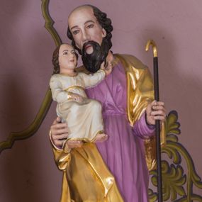 Zdjęcie nr 1: Rzeźba św. Joachima została ścięta z tyłu i wydrążona. Joachim został ujęty frontalnie, w kontrapoście, z głową przechyloną w lewo. Na prawym przedramieniu podtrzymuje Dzieciątko, a w lewej ręce trzyma zakrzywioną laskę. Ma pociągłą twarz o wysokim czole, migdałowatych oczach, prostym nosie, okoloną brodą i włosami po bokach głowy. Na czubku głowy widoczna jest łysina. Święty ubrany jest w fioletową tunikę oraz pozłocony płaszcz zarzucony na ramiona, opadający na plecy i na prawy bok. Spod tuniki widać jego bose stopy. Dzieciątko ukazano w pozycji siedzącej, lewą rączką wyciąga w stronę twarzy Symeona, a prawą przed siebie. Mały Jezus ubrany jest w białą tunikę ze złotą lamówką.
