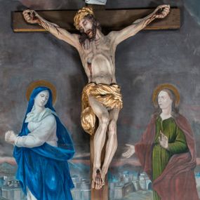 Zdjęcie nr 1: Malarsko-rzeźbiarska scena Ukrzyżowania w polu w kształcie stojącego prostokąta. Pełnoplastyczna figura Ukrzyżowanego w typie Christo morto. Głowa mocno pochylona w prawo, pociągła, wyraziście modelowana twarz o długim, prostym nosie, rozchylonych ustach i krótkim, ciemnobrązowym zaroście. Długie, falowane włosy opadają na prawe ramię. Głowę wieńczy wydatna, złocona korona. Ciało o wyrazistej, plastycznie opracowanej muskulaturze i delikatnie zaznaczonej linii żeber, z drobną fałdką pośrodku brzucha. Biodra przewiązane krótkim, silnie drapowanym, złoconym perizonium z długim zwisem na prawym boku. Zgięte w kolanach, lekko przechylone w lewo nogi przybite są 1 gwoździem. Na czole i klatce piersiowej drobnie ślady krwi, na rękach, prawym boku i stopach wydatne strugi. W górnej partii krzyża biały titulus w formie zwoju z napisem „I.N. / R.I”. Figury asystencyjne namalowane na tle rozległego pejzażu miasta i ciemnego nieba z zaćmionym słońce w lewym, górnym rogu. Po prawej stronie krzyża stoi Matka Boska skierowana w trzech czwartych w prawo odwracając się w za siebie. Owalna twarz o delikatnych rysach, oczy półprzymknięte. Ubrana w jasnoróżową suknię, narzucony na głowę ciemnoniebieski płaszcz i okalającą szyję białą chustę. Ręce złocone w geście modlitwy. Po lewej stronie krzyża stoi św. Jan Ewangelista zwrócony w trzech czwartych w prawo. Owalna twarz o delikatnych rysach, wzrok skierowany na wprost, z oczu płyną krople łez. Falowane włosy opadają na ramiona. Ubrany jest w zieloną, przewiązana w pasie suknię i bordowy, narzucony na ramiona płaszcz. na stopach sandały. Prawa ręka uniesiona na wysokości talii, lewa odsunięta w bok. Głowę Marii i sw. Jana okalają złocone nimby.   