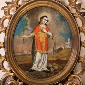 Zdjęcie nr 1: Obraz w kształcie stojącego owalu przedstawia całopostaciowy wizerunek św. Szczepana stojącego w kontrapoście i zwróconego w trzech czwartych w lewo. Przechyloną głowę charakteryzuje owalna twarz o młodzieńczych, pozbawionych zarostu rysach oraz długie, falowane, opadające na plecy włosy. Święty ubrany jest w albę i czerwoną dalmatykę ze złoconymi obszyciami i pretekstą w formie krzyża. Lewą rękę wspiera na piersiach, w prawej wysuniętej w bok trzyma gałązkę palmową. Głowę świętego okala świetlisty nimb, u jego stóp, po prawej stronie leżą trzy kamienie. Święty Szczepan ukazany jest na tle górzystego pejzażu o obniżonej linii horyzontu, z elementami architektury po prawej stronie kompozycji, gdzie wyróżnia się strzelista wieża kościoła. Znaczną część tła zajmuje partia pokrytego obłokami nieba. W dolnej części obrazu znajduje się napis „S(anctus) Stephanus M(artyr)”.       
Obraz ujęty jest rzeźbioną, ażurową ramą z motywem rocaille’u, parą wolut po bokach u dołu oraz motywem kartusza w zwieńczeniu. Całość osadzona jest wtórnie na sarkofagowym ołtarzu w formie niewielkiej konsoli.   