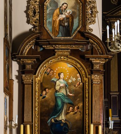 Zdjęcie nr 1: Ołtarz architektoniczny, jednokondygnacyjny, jednoosiowy, ze zwieńczeniem. Ołtarz prostopadłościenny z drewnianą mensą i drewnianym antepedium artykułowanym trzema prostokątnymi płycinami. Retabulum osadzone na lekko zryzalitowanym cokole, lekko wstępującym pośrodku w kolejną partię retabulum. Część środkową ołtarza ujmuje para filarów o czworobocznym przekroju, osadzonych na wysokich cokołach i podtrzymujących przerwane belkowanie ze wspartym na nim przerwanym, półkolistym przyczółkiem. Część środkowa belkowania jest wyniesiona nieco wyżej. Pole części środkowej ma kształt stojącego prostokąta zamkniętego półkolistym łukiem nadwieszonym. Osadzone na wyłamującym się pośrodku gzymsie zwieńczenie jest w formie stojącego prostokąta wypełnionego płyciną z uszakami w narożach, zamkniętą trapezoidalnym łukiem. Pole środkowe ma postać wydłużonego ośmioboku. Zwieńczenie zamyka szczyt w formie przerwanego, trójkątnego przyczółka osadzonego na przerwanym belkowaniu. Partie fryzu retabulum zdobi motyw prostokątnych rozet. Boki zwieńczenia zdobi para ażurowych, ornamentalnych uszaków. W szczycie, pośrodku, na niewielkim cokoliku znajduje się monogram maryjny dołem ujęty bukietem kwiatów, górą koroną. W polu części środkowej umieszczono obraz Matki Boskiej Niepokalanie Poczętej, na zasuwie wizerunek Matki Boskiej Bolesnej. W zwieńczeniu jest przedstawienie św. Józefa. Struktura retabulum utrzymana jest w kolorystyce pokostowanego drewna, partie detalu architektonicznego i ornamentyka są złocone.   

