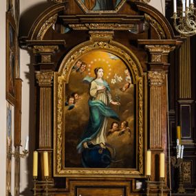 Zdjęcie nr 1: Ołtarz architektoniczny, jednokondygnacyjny, jednoosiowy, ze zwieńczeniem. Ołtarz prostopadłościenny z drewnianą mensą i drewnianym antepedium artykułowanym trzema prostokątnymi płycinami. Retabulum osadzone na lekko zryzalitowanym cokole, lekko wstępującym pośrodku w kolejną partię retabulum. Część środkową ołtarza ujmuje para filarów o czworobocznym przekroju, osadzonych na wysokich cokołach i podtrzymujących przerwane belkowanie ze wspartym na nim przerwanym, półkolistym przyczółkiem. Część środkowa belkowania jest wyniesiona nieco wyżej. Pole części środkowej ma kształt stojącego prostokąta zamkniętego półkolistym łukiem nadwieszonym. Osadzone na wyłamującym się pośrodku gzymsie zwieńczenie jest w formie stojącego prostokąta wypełnionego płyciną z uszakami w narożach, zamkniętą trapezoidalnym łukiem. Pole środkowe ma postać wydłużonego ośmioboku. Zwieńczenie zamyka szczyt w formie przerwanego, trójkątnego przyczółka osadzonego na przerwanym belkowaniu. Partie fryzu retabulum zdobi motyw prostokątnych rozet. Boki zwieńczenia zdobi para ażurowych, ornamentalnych uszaków. W szczycie, pośrodku, na niewielkim cokoliku znajduje się monogram maryjny dołem ujęty bukietem kwiatów, górą koroną. W polu części środkowej umieszczono obraz Matki Boskiej Niepokalanie Poczętej, na zasuwie wizerunek Matki Boskiej Bolesnej. W zwieńczeniu jest przedstawienie św. Józefa. Struktura retabulum utrzymana jest w kolorystyce pokostowanego drewna, partie detalu architektonicznego i ornamentyka są złocone.   

