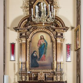 Zdjęcie nr 1: Ołtarz architektoniczny, jednokondygnacyjny, jednoosiowy, ze zwieńczeniem. Ołtarz prostopadłościenny z drewnianą mensą i drewnianym antepedium artykułowanym trzema prostokątnymi płycinami. Retabulum osadzone na nieznacznie zryzalitowanym cokole, lekko wstępującym pośrodku w kolejną partię retabulum. Część środkową ołtarza ujmuje para filarów o czworobocznym przekroju, ustawionych na tle pilastrów, osadzonych na wysokich cokołach i podtrzymujących przerwane belkowanie ze wspartym na nim przerwanym, półkolistym przyczółkiem. Część środkowa belkowania jest wyniesiona nieco wyżej. Pole części środkowej ma kształt stojącego prostokąta zamkniętego półkolistym łukiem nadwieszonym. Osadzone na wyłamującym się pośrodku gzymsie zwieńczenie ma postać stojącego prostokąta wypełnionego płyciną z uszakami w narożach, zamkniętą trójbocznie z ośmioboku. Pole środkowe w formie wydłużonego ośmioboku. Zwieńczenie domyka szczyt z formie przerwanego, trójkątnego przyczółka osadzonego na przerwanym belkowaniu. Środkową płycinę antepedium zdobi płaskorzeźbiony motyw gorejącego serca Jezusa ujęty promienistą glorią. W partii fryzu są motywy ornamentyki roślinnej. Boki zwieńczenia ujmuje para ażurowych, akantowych uszaków. W szczycie, po bokach, na przerwanym przyczółku jest para płonących wazonów, pośrodku natomiast monogram IHS z krzyżem. W polu części środkowej znajduje się przedstawienie św. Małgorzaty Alacoque adorującej Najświętsze Serce Jezusa. W zwieńczeniu jest przedstawienie (?). Struktura retabulum utrzymana jest w kolorystyce pokostowanego drewna, partie detalu architektonicznego i ornamentyka są złocone.  