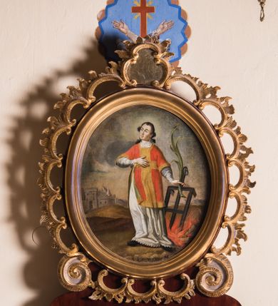 Zdjęcie nr 1: Obraz w kształcie stojącego owalu przedstawia całopostaciowy wizerunek św. Wawrzyńca stojącego w kontrapoście i zwróconego w trzech czwartych w prawo. Przechyloną nieznacznie głowę charakteryzuje pociągła twarz o wyrazistych, młodzieńczych, pozbawionych zarostu rysach oraz długie, falowane, opadające na plecy włosy o wydatnych kępkach na wysokości uszu. Święty ubrany jest w albę i czerwoną dalmatykę ze złoconymi obszyciami i pretekstą w formie krzyża. Prawą rękę wspiera na piersiach, w lewej, wysuniętej w bok trzyma gałązkę palmową i kratę paleniskową wetkniętą w płonące ognisko. Głowę świętego okala jasny, świetlisty nimb. Święty Wawrzyniec ukazany jest na tle górzystego pejzażu o obniżonej linii horyzontu, z elementami architektury otoczonego murem miasta po lewej stronie kompozycji. Znaczną część tła zajmuje partia pokrytego obłokami nieba. W dolnej części obrazu znajduje się napis „S(anctus) Laurentius M(artyr)”.  
Obraz ujęty jest rzeźbioną, ażurową ramą z motywem rocaille’u, parą wolut po bokach u dołu oraz motywem kartusza w zwieńczeniu. Całość osadzona jest wtórnie na sarkofagowym ołtarzu w formie niewielkiej konsoli.   

