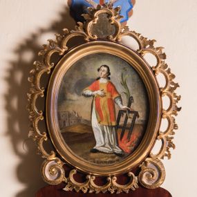 Zdjęcie nr 1: Obraz w kształcie stojącego owalu przedstawia całopostaciowy wizerunek św. Wawrzyńca stojącego w kontrapoście i zwróconego w trzech czwartych w prawo. Przechyloną nieznacznie głowę charakteryzuje pociągła twarz o wyrazistych, młodzieńczych, pozbawionych zarostu rysach oraz długie, falowane, opadające na plecy włosy o wydatnych kępkach na wysokości uszu. Święty ubrany jest w albę i czerwoną dalmatykę ze złoconymi obszyciami i pretekstą w formie krzyża. Prawą rękę wspiera na piersiach, w lewej, wysuniętej w bok trzyma gałązkę palmową i kratę paleniskową wetkniętą w płonące ognisko. Głowę świętego okala jasny, świetlisty nimb. Święty Wawrzyniec ukazany jest na tle górzystego pejzażu o obniżonej linii horyzontu, z elementami architektury otoczonego murem miasta po lewej stronie kompozycji. Znaczną część tła zajmuje partia pokrytego obłokami nieba. W dolnej części obrazu znajduje się napis „S(anctus) Laurentius M(artyr)”.  
Obraz ujęty jest rzeźbioną, ażurową ramą z motywem rocaille’u, parą wolut po bokach u dołu oraz motywem kartusza w zwieńczeniu. Całość osadzona jest wtórnie na sarkofagowym ołtarzu w formie niewielkiej konsoli.   

