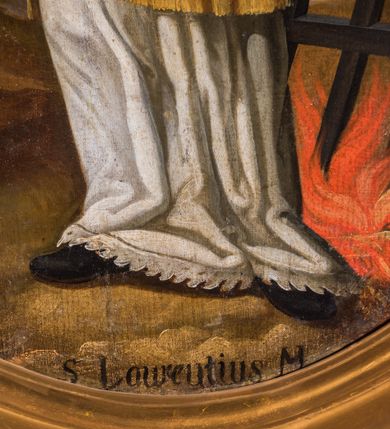 Zdjęcie nr 6: Obraz w kształcie stojącego owalu przedstawia całopostaciowy wizerunek św. Wawrzyńca stojącego w kontrapoście i zwróconego w trzech czwartych w prawo. Przechyloną nieznacznie głowę charakteryzuje pociągła twarz o wyrazistych, młodzieńczych, pozbawionych zarostu rysach oraz długie, falowane, opadające na plecy włosy o wydatnych kępkach na wysokości uszu. Święty ubrany jest w albę i czerwoną dalmatykę ze złoconymi obszyciami i pretekstą w formie krzyża. Prawą rękę wspiera na piersiach, w lewej, wysuniętej w bok trzyma gałązkę palmową i kratę paleniskową wetkniętą w płonące ognisko. Głowę świętego okala jasny, świetlisty nimb. Święty Wawrzyniec ukazany jest na tle górzystego pejzażu o obniżonej linii horyzontu, z elementami architektury otoczonego murem miasta po lewej stronie kompozycji. Znaczną część tła zajmuje partia pokrytego obłokami nieba. W dolnej części obrazu znajduje się napis „S(anctus) Laurentius M(artyr)”.  
Obraz ujęty jest rzeźbioną, ażurową ramą z motywem rocaille’u, parą wolut po bokach u dołu oraz motywem kartusza w zwieńczeniu. Całość osadzona jest wtórnie na sarkofagowym ołtarzu w formie niewielkiej konsoli.   

