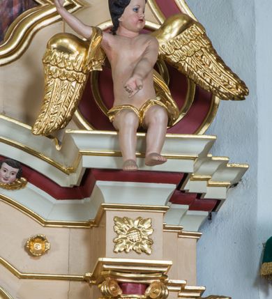 Zdjęcie nr 7: Przyścienny ołtarz drewniany, jednoosiowy ze zwieńczeniem otrzymał formę architektoniczną. Nastawa wspiera się na nowym, prostopadłościennym stipesie marmurowym z mensą, artykułowany od przodu dwiema smukłymi półkolumienkami, pomiędzy którymi umieszczono metalową i złoconą aplikację z przedstawieniem Najświętszego Serca Pana Jezusa. Na mensie ustawiono tabernakulum w formie prostopadłościennej skrzynki z drzwiczkami ozdobionymi płaskorzeźbionym kielichem z hostią, które otacza winna latorośl. Jednokondygnacyjną nastawę ustawiono na dwustrefowym cokole. Partia cokołu ozdobiona została płycinami w kształcie pionowych prostokątów, a w osi środkowej w kształcie kwadratów. Płyciny wypełniono rzeźbioną dekoracją floralną na czerwonym tle. Kondygnacja retabulum ujęta została parą złoconych kolumn, podtrzymujących wyłamane nad polem środkowym belkowanie. Kolumny o kompozytowych kapitelach ustawiono na profilowanych bazach, w jednej trzeciej wysokości przedzielone zostały opaską. W części dolnej ozdobiono je żłobkowaniem. Na belkowaniu umieszczono parę uskrzydlonych aniołków. Pole środkowe ujęte zostało w prostokątną, profilowaną ramę, zamkniętą od góry łukiem wklęsło-wypukłym z uskokami. W niej prezentowany jest obraz Matki Boskiej Częstochowskiej w drewnianej, złoconej sukience wotywnej. Po bokach nastawy umieszczono ażurowe, złocone wici akantowe pełniące role uszaków. Zwieńczenie uzyskało formę prostokąta stojącego, ujętego po bokach  dwiema lizenami i spływami wolutowymi. Wieńczy je przerywane belkowanie, na którym usytuowano parę siedzących aniołków. W polu zwieńczenia umieszczono obraz św. Agaty we wklęsło-wypukłej ramie. Natomiast szczyt zwieńczenia ozdobiono złoconym monogramem maryjnym na czerwonym tle, otoczonym wieńcem z obłoków i promienistą glorią. Strukturę nastawy pomalowano w kolorze beżowym, a ornamentykę wyzłocono i wysrebrzono.