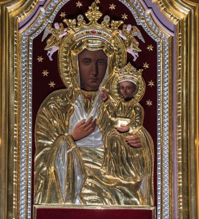 Zdjęcie nr 5: Przyścienny ołtarz drewniany, jednoosiowy ze zwieńczeniem otrzymał formę architektoniczną. Nastawa wspiera się na nowym, prostopadłościennym stipesie marmurowym z mensą, artykułowany od przodu dwiema smukłymi półkolumienkami, pomiędzy którymi umieszczono metalową i złoconą aplikację z przedstawieniem Najświętszego Serca Pana Jezusa. Na mensie ustawiono tabernakulum w formie prostopadłościennej skrzynki z drzwiczkami ozdobionymi płaskorzeźbionym kielichem z hostią, które otacza winna latorośl. Jednokondygnacyjną nastawę ustawiono na dwustrefowym cokole. Partia cokołu ozdobiona została płycinami w kształcie pionowych prostokątów, a w osi środkowej w kształcie kwadratów. Płyciny wypełniono rzeźbioną dekoracją floralną na czerwonym tle. Kondygnacja retabulum ujęta została parą złoconych kolumn, podtrzymujących wyłamane nad polem środkowym belkowanie. Kolumny o kompozytowych kapitelach ustawiono na profilowanych bazach, w jednej trzeciej wysokości przedzielone zostały opaską. W części dolnej ozdobiono je żłobkowaniem. Na belkowaniu umieszczono parę uskrzydlonych aniołków. Pole środkowe ujęte zostało w prostokątną, profilowaną ramę, zamkniętą od góry łukiem wklęsło-wypukłym z uskokami. W niej prezentowany jest obraz Matki Boskiej Częstochowskiej w drewnianej, złoconej sukience wotywnej. Po bokach nastawy umieszczono ażurowe, złocone wici akantowe pełniące role uszaków. Zwieńczenie uzyskało formę prostokąta stojącego, ujętego po bokach  dwiema lizenami i spływami wolutowymi. Wieńczy je przerywane belkowanie, na którym usytuowano parę siedzących aniołków. W polu zwieńczenia umieszczono obraz św. Agaty we wklęsło-wypukłej ramie. Natomiast szczyt zwieńczenia ozdobiono złoconym monogramem maryjnym na czerwonym tle, otoczonym wieńcem z obłoków i promienistą glorią. Strukturę nastawy pomalowano w kolorze beżowym, a ornamentykę wyzłocono i wysrebrzono.