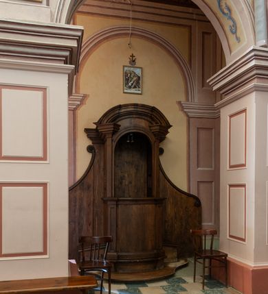 Zdjęcie nr 3: Konfesjonał o fantazyjnie wyciętej podstawie. Siedzisko ustawione na niskim cokole z drzwiczkami lekko wybrzuszonymi, ujętymi po bokach pilastrami, zdobionymi prostokątną płyciną i zamkniętymi profilowanym gzymsem. Powyżej pilastry zdobione kanelowaniem, zwieńczone wydatnymi, profilowanymi i ustawionymi pod kątem impostami. Przyczółek półkolisty, silnie profilowany. Ścianki zaplecka szerokie, zdobione wydłużonymi wolutami. W ściankach flankujących z boków siedzisko księdza prześwity z kratą.
