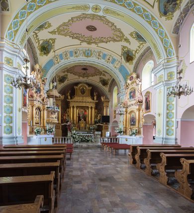 Zdjęcie nr 20: Orientowany kościół św. Wojciecha w Bulowicach obecnie uzyskał strukturę trójnawowej, trójprzęsłowej bazyliki z jednoprzęsłowym, nieco węższym prezbiterium zamkniętym spłaszczoną absydą. Na przedłużeniu dostawionych naw wybudowano półkolisty aneks zakrystyjny okalający apsydę, przepruwając go trzema półokrągłymi oknami oraz wejściem na osi. W aneksie od strony południowo-wschodniej urządzono otwartą na zewnątrz półkolistą arkadą kaplicę Ogrójcową. Od zachodu do nawy głównej przylega lekko wysunięta do przodu czworoboczna wieża flankowana dwoma, piętrowymi aneksami. Elewację masywu wieżowego artykułuje profilowany gzyms koronujący wyłamany na szerokości wieży, podtrzymujący miedziany daszek pulpitowy, dzielący ją na dwie kondygnacje. Podobny gzyms zamyka wieżę u góry, ponad którym wznosi się cebulasty hełm zwieńczony krzyżem na bani. Pod gzymsem w górnej części wieży usytuowano tarcze zegarowe oraz poniżej półokrągłe okna. W jej przyziemiu urządzono kruchtę, do której prowadzi portal uszaty z widocznym nad nim odcinkiem belkowania. Za pomocą symetrycznych spływów dostawione dwie nawy zostały połączone w spójną całość z masywem wieżowym. Do obu naw prowadzą półokrągłe arkady, w których urządzono otwarte przedsionki poprzedzające weście do kościoła. Nawę główną i prezbiterium nakryto dachem siodłowym. W jej części wschodniej nadwieszono wieżyczkę na sygnaturkę w kształcie sześciobocznej latarnii z baniastym hełmem i krzyżem. Nawy boczne i aneks zakrystyjny przykryto dachami pulpitowymi. Elewacje zewnętrzne zostały pozbawione artykulacji za wyjątkiem niskiego kamiennego cokołu obiegającego całą świątynię. Wnętrze nawy głównej zostało rozczłonkowane za pomocą opilastrowanych filarów, ponad którymi widoczne są odcinki belkowania. W tęczy kościoła zastosowano pilastry zdwojone. Nawy boczne połączono z nawą główną za pomocą mocno spłaszczonych arkad. Ponad nimi przepruto prostokątne okna zamknięte łukiem odcinkowym. Całość nawy nakryto sklepieniem żagielkowym wspartym na gurtach, zaś prezbiterium przykryto hemisferycznie. W części zachodniej nawy głównej zawieszono chór muzyczny wsparty na dwóch drewnianych filarach z drewnianym, pełnym parapetem artykułowanym czworobocznymi płycinami. Na osi środkowej parapet wyłamano na rzucie trapezu. W prezbiterium ustawiono ołtarz główny, a przy łuku tęczowym dwa ołtarze boczne. Na północnej ścianie łuku tęczowego zawieszono ambonę. Dwa niewielkie ołtarze boczne znalazły się także na zakończeniu naw bocznych.   