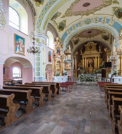 Zdjęcie nr 4: Orientowany kościół św. Wojciecha w Bulowicach obecnie uzyskał strukturę trójnawowej, trójprzęsłowej bazyliki z jednoprzęsłowym, nieco węższym prezbiterium zamkniętym spłaszczoną absydą. Na przedłużeniu dostawionych naw wybudowano półkolisty aneks zakrystyjny okalający apsydę, przepruwając go trzema półokrągłymi oknami oraz wejściem na osi. W aneksie od strony południowo-wschodniej urządzono otwartą na zewnątrz półkolistą arkadą kaplicę Ogrójcową. Od zachodu do nawy głównej przylega lekko wysunięta do przodu czworoboczna wieża flankowana dwoma, piętrowymi aneksami. Elewację masywu wieżowego artykułuje profilowany gzyms koronujący wyłamany na szerokości wieży, podtrzymujący miedziany daszek pulpitowy, dzielący ją na dwie kondygnacje. Podobny gzyms zamyka wieżę u góry, ponad którym wznosi się cebulasty hełm zwieńczony krzyżem na bani. Pod gzymsem w górnej części wieży usytuowano tarcze zegarowe oraz poniżej półokrągłe okna. W jej przyziemiu urządzono kruchtę, do której prowadzi portal uszaty z widocznym nad nim odcinkiem belkowania. Za pomocą symetrycznych spływów dostawione dwie nawy zostały połączone w spójną całość z masywem wieżowym. Do obu naw prowadzą półokrągłe arkady, w których urządzono otwarte przedsionki poprzedzające weście do kościoła. Nawę główną i prezbiterium nakryto dachem siodłowym. W jej części wschodniej nadwieszono wieżyczkę na sygnaturkę w kształcie sześciobocznej latarnii z baniastym hełmem i krzyżem. Nawy boczne i aneks zakrystyjny przykryto dachami pulpitowymi. Elewacje zewnętrzne zostały pozbawione artykulacji za wyjątkiem niskiego kamiennego cokołu obiegającego całą świątynię. Wnętrze nawy głównej zostało rozczłonkowane za pomocą opilastrowanych filarów, ponad którymi widoczne są odcinki belkowania. W tęczy kościoła zastosowano pilastry zdwojone. Nawy boczne połączono z nawą główną za pomocą mocno spłaszczonych arkad. Ponad nimi przepruto prostokątne okna zamknięte łukiem odcinkowym. Całość nawy nakryto sklepieniem żagielkowym wspartym na gurtach, zaś prezbiterium przykryto hemisferycznie. W części zachodniej nawy głównej zawieszono chór muzyczny wsparty na dwóch drewnianych filarach z drewnianym, pełnym parapetem artykułowanym czworobocznymi płycinami. Na osi środkowej parapet wyłamano na rzucie trapezu. W prezbiterium ustawiono ołtarz główny, a przy łuku tęczowym dwa ołtarze boczne. Na północnej ścianie łuku tęczowego zawieszono ambonę. Dwa niewielkie ołtarze boczne znalazły się także na zakończeniu naw bocznych.   