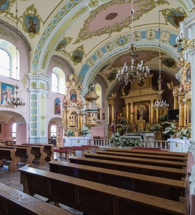 Zdjęcie nr 6: Orientowany kościół św. Wojciecha w Bulowicach obecnie uzyskał strukturę trójnawowej, trójprzęsłowej bazyliki z jednoprzęsłowym, nieco węższym prezbiterium zamkniętym spłaszczoną absydą. Na przedłużeniu dostawionych naw wybudowano półkolisty aneks zakrystyjny okalający apsydę, przepruwając go trzema półokrągłymi oknami oraz wejściem na osi. W aneksie od strony południowo-wschodniej urządzono otwartą na zewnątrz półkolistą arkadą kaplicę Ogrójcową. Od zachodu do nawy głównej przylega lekko wysunięta do przodu czworoboczna wieża flankowana dwoma, piętrowymi aneksami. Elewację masywu wieżowego artykułuje profilowany gzyms koronujący wyłamany na szerokości wieży, podtrzymujący miedziany daszek pulpitowy, dzielący ją na dwie kondygnacje. Podobny gzyms zamyka wieżę u góry, ponad którym wznosi się cebulasty hełm zwieńczony krzyżem na bani. Pod gzymsem w górnej części wieży usytuowano tarcze zegarowe oraz poniżej półokrągłe okna. W jej przyziemiu urządzono kruchtę, do której prowadzi portal uszaty z widocznym nad nim odcinkiem belkowania. Za pomocą symetrycznych spływów dostawione dwie nawy zostały połączone w spójną całość z masywem wieżowym. Do obu naw prowadzą półokrągłe arkady, w których urządzono otwarte przedsionki poprzedzające weście do kościoła. Nawę główną i prezbiterium nakryto dachem siodłowym. W jej części wschodniej nadwieszono wieżyczkę na sygnaturkę w kształcie sześciobocznej latarnii z baniastym hełmem i krzyżem. Nawy boczne i aneks zakrystyjny przykryto dachami pulpitowymi. Elewacje zewnętrzne zostały pozbawione artykulacji za wyjątkiem niskiego kamiennego cokołu obiegającego całą świątynię. Wnętrze nawy głównej zostało rozczłonkowane za pomocą opilastrowanych filarów, ponad którymi widoczne są odcinki belkowania. W tęczy kościoła zastosowano pilastry zdwojone. Nawy boczne połączono z nawą główną za pomocą mocno spłaszczonych arkad. Ponad nimi przepruto prostokątne okna zamknięte łukiem odcinkowym. Całość nawy nakryto sklepieniem żagielkowym wspartym na gurtach, zaś prezbiterium przykryto hemisferycznie. W części zachodniej nawy głównej zawieszono chór muzyczny wsparty na dwóch drewnianych filarach z drewnianym, pełnym parapetem artykułowanym czworobocznymi płycinami. Na osi środkowej parapet wyłamano na rzucie trapezu. W prezbiterium ustawiono ołtarz główny, a przy łuku tęczowym dwa ołtarze boczne. Na północnej ścianie łuku tęczowego zawieszono ambonę. Dwa niewielkie ołtarze boczne znalazły się także na zakończeniu naw bocznych.   