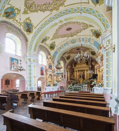 Zdjęcie nr 7: Orientowany kościół św. Wojciecha w Bulowicach obecnie uzyskał strukturę trójnawowej, trójprzęsłowej bazyliki z jednoprzęsłowym, nieco węższym prezbiterium zamkniętym spłaszczoną absydą. Na przedłużeniu dostawionych naw wybudowano półkolisty aneks zakrystyjny okalający apsydę, przepruwając go trzema półokrągłymi oknami oraz wejściem na osi. W aneksie od strony południowo-wschodniej urządzono otwartą na zewnątrz półkolistą arkadą kaplicę Ogrójcową. Od zachodu do nawy głównej przylega lekko wysunięta do przodu czworoboczna wieża flankowana dwoma, piętrowymi aneksami. Elewację masywu wieżowego artykułuje profilowany gzyms koronujący wyłamany na szerokości wieży, podtrzymujący miedziany daszek pulpitowy, dzielący ją na dwie kondygnacje. Podobny gzyms zamyka wieżę u góry, ponad którym wznosi się cebulasty hełm zwieńczony krzyżem na bani. Pod gzymsem w górnej części wieży usytuowano tarcze zegarowe oraz poniżej półokrągłe okna. W jej przyziemiu urządzono kruchtę, do której prowadzi portal uszaty z widocznym nad nim odcinkiem belkowania. Za pomocą symetrycznych spływów dostawione dwie nawy zostały połączone w spójną całość z masywem wieżowym. Do obu naw prowadzą półokrągłe arkady, w których urządzono otwarte przedsionki poprzedzające weście do kościoła. Nawę główną i prezbiterium nakryto dachem siodłowym. W jej części wschodniej nadwieszono wieżyczkę na sygnaturkę w kształcie sześciobocznej latarnii z baniastym hełmem i krzyżem. Nawy boczne i aneks zakrystyjny przykryto dachami pulpitowymi. Elewacje zewnętrzne zostały pozbawione artykulacji za wyjątkiem niskiego kamiennego cokołu obiegającego całą świątynię. Wnętrze nawy głównej zostało rozczłonkowane za pomocą opilastrowanych filarów, ponad którymi widoczne są odcinki belkowania. W tęczy kościoła zastosowano pilastry zdwojone. Nawy boczne połączono z nawą główną za pomocą mocno spłaszczonych arkad. Ponad nimi przepruto prostokątne okna zamknięte łukiem odcinkowym. Całość nawy nakryto sklepieniem żagielkowym wspartym na gurtach, zaś prezbiterium przykryto hemisferycznie. W części zachodniej nawy głównej zawieszono chór muzyczny wsparty na dwóch drewnianych filarach z drewnianym, pełnym parapetem artykułowanym czworobocznymi płycinami. Na osi środkowej parapet wyłamano na rzucie trapezu. W prezbiterium ustawiono ołtarz główny, a przy łuku tęczowym dwa ołtarze boczne. Na północnej ścianie łuku tęczowego zawieszono ambonę. Dwa niewielkie ołtarze boczne znalazły się także na zakończeniu naw bocznych.   