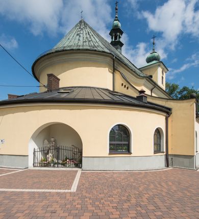 Zdjęcie nr 18: Orientowany kościół św. Wojciecha w Bulowicach obecnie uzyskał strukturę trójnawowej, trójprzęsłowej bazyliki z jednoprzęsłowym, nieco węższym prezbiterium zamkniętym spłaszczoną absydą. Na przedłużeniu dostawionych naw wybudowano półkolisty aneks zakrystyjny okalający apsydę, przepruwając go trzema półokrągłymi oknami oraz wejściem na osi. W aneksie od strony południowo-wschodniej urządzono otwartą na zewnątrz półkolistą arkadą kaplicę Ogrójcową. Od zachodu do nawy głównej przylega lekko wysunięta do przodu czworoboczna wieża flankowana dwoma, piętrowymi aneksami. Elewację masywu wieżowego artykułuje profilowany gzyms koronujący wyłamany na szerokości wieży, podtrzymujący miedziany daszek pulpitowy, dzielący ją na dwie kondygnacje. Podobny gzyms zamyka wieżę u góry, ponad którym wznosi się cebulasty hełm zwieńczony krzyżem na bani. Pod gzymsem w górnej części wieży usytuowano tarcze zegarowe oraz poniżej półokrągłe okna. W jej przyziemiu urządzono kruchtę, do której prowadzi portal uszaty z widocznym nad nim odcinkiem belkowania. Za pomocą symetrycznych spływów dostawione dwie nawy zostały połączone w spójną całość z masywem wieżowym. Do obu naw prowadzą półokrągłe arkady, w których urządzono otwarte przedsionki poprzedzające weście do kościoła. Nawę główną i prezbiterium nakryto dachem siodłowym. W jej części wschodniej nadwieszono wieżyczkę na sygnaturkę w kształcie sześciobocznej latarnii z baniastym hełmem i krzyżem. Nawy boczne i aneks zakrystyjny przykryto dachami pulpitowymi. Elewacje zewnętrzne zostały pozbawione artykulacji za wyjątkiem niskiego kamiennego cokołu obiegającego całą świątynię. Wnętrze nawy głównej zostało rozczłonkowane za pomocą opilastrowanych filarów, ponad którymi widoczne są odcinki belkowania. W tęczy kościoła zastosowano pilastry zdwojone. Nawy boczne połączono z nawą główną za pomocą mocno spłaszczonych arkad. Ponad nimi przepruto prostokątne okna zamknięte łukiem odcinkowym. Całość nawy nakryto sklepieniem żagielkowym wspartym na gurtach, zaś prezbiterium przykryto hemisferycznie. W części zachodniej nawy głównej zawieszono chór muzyczny wsparty na dwóch drewnianych filarach z drewnianym, pełnym parapetem artykułowanym czworobocznymi płycinami. Na osi środkowej parapet wyłamano na rzucie trapezu. W prezbiterium ustawiono ołtarz główny, a przy łuku tęczowym dwa ołtarze boczne. Na północnej ścianie łuku tęczowego zawieszono ambonę. Dwa niewielkie ołtarze boczne znalazły się także na zakończeniu naw bocznych.   