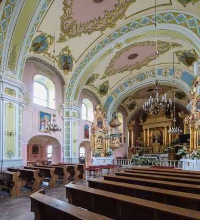 Zdjęcie nr 8: Orientowany kościół św. Wojciecha w Bulowicach obecnie uzyskał strukturę trójnawowej, trójprzęsłowej bazyliki z jednoprzęsłowym, nieco węższym prezbiterium zamkniętym spłaszczoną absydą. Na przedłużeniu dostawionych naw wybudowano półkolisty aneks zakrystyjny okalający apsydę, przepruwając go trzema półokrągłymi oknami oraz wejściem na osi. W aneksie od strony południowo-wschodniej urządzono otwartą na zewnątrz półkolistą arkadą kaplicę Ogrójcową. Od zachodu do nawy głównej przylega lekko wysunięta do przodu czworoboczna wieża flankowana dwoma, piętrowymi aneksami. Elewację masywu wieżowego artykułuje profilowany gzyms koronujący wyłamany na szerokości wieży, podtrzymujący miedziany daszek pulpitowy, dzielący ją na dwie kondygnacje. Podobny gzyms zamyka wieżę u góry, ponad którym wznosi się cebulasty hełm zwieńczony krzyżem na bani. Pod gzymsem w górnej części wieży usytuowano tarcze zegarowe oraz poniżej półokrągłe okna. W jej przyziemiu urządzono kruchtę, do której prowadzi portal uszaty z widocznym nad nim odcinkiem belkowania. Za pomocą symetrycznych spływów dostawione dwie nawy zostały połączone w spójną całość z masywem wieżowym. Do obu naw prowadzą półokrągłe arkady, w których urządzono otwarte przedsionki poprzedzające weście do kościoła. Nawę główną i prezbiterium nakryto dachem siodłowym. W jej części wschodniej nadwieszono wieżyczkę na sygnaturkę w kształcie sześciobocznej latarnii z baniastym hełmem i krzyżem. Nawy boczne i aneks zakrystyjny przykryto dachami pulpitowymi. Elewacje zewnętrzne zostały pozbawione artykulacji za wyjątkiem niskiego kamiennego cokołu obiegającego całą świątynię. Wnętrze nawy głównej zostało rozczłonkowane za pomocą opilastrowanych filarów, ponad którymi widoczne są odcinki belkowania. W tęczy kościoła zastosowano pilastry zdwojone. Nawy boczne połączono z nawą główną za pomocą mocno spłaszczonych arkad. Ponad nimi przepruto prostokątne okna zamknięte łukiem odcinkowym. Całość nawy nakryto sklepieniem żagielkowym wspartym na gurtach, zaś prezbiterium przykryto hemisferycznie. W części zachodniej nawy głównej zawieszono chór muzyczny wsparty na dwóch drewnianych filarach z drewnianym, pełnym parapetem artykułowanym czworobocznymi płycinami. Na osi środkowej parapet wyłamano na rzucie trapezu. W prezbiterium ustawiono ołtarz główny, a przy łuku tęczowym dwa ołtarze boczne. Na północnej ścianie łuku tęczowego zawieszono ambonę. Dwa niewielkie ołtarze boczne znalazły się także na zakończeniu naw bocznych.   