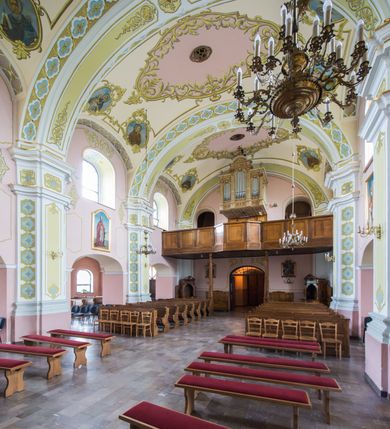 Zdjęcie nr 12: Orientowany kościół św. Wojciecha w Bulowicach obecnie uzyskał strukturę trójnawowej, trójprzęsłowej bazyliki z jednoprzęsłowym, nieco węższym prezbiterium zamkniętym spłaszczoną absydą. Na przedłużeniu dostawionych naw wybudowano półkolisty aneks zakrystyjny okalający apsydę, przepruwając go trzema półokrągłymi oknami oraz wejściem na osi. W aneksie od strony południowo-wschodniej urządzono otwartą na zewnątrz półkolistą arkadą kaplicę Ogrójcową. Od zachodu do nawy głównej przylega lekko wysunięta do przodu czworoboczna wieża flankowana dwoma, piętrowymi aneksami. Elewację masywu wieżowego artykułuje profilowany gzyms koronujący wyłamany na szerokości wieży, podtrzymujący miedziany daszek pulpitowy, dzielący ją na dwie kondygnacje. Podobny gzyms zamyka wieżę u góry, ponad którym wznosi się cebulasty hełm zwieńczony krzyżem na bani. Pod gzymsem w górnej części wieży usytuowano tarcze zegarowe oraz poniżej półokrągłe okna. W jej przyziemiu urządzono kruchtę, do której prowadzi portal uszaty z widocznym nad nim odcinkiem belkowania. Za pomocą symetrycznych spływów dostawione dwie nawy zostały połączone w spójną całość z masywem wieżowym. Do obu naw prowadzą półokrągłe arkady, w których urządzono otwarte przedsionki poprzedzające weście do kościoła. Nawę główną i prezbiterium nakryto dachem siodłowym. W jej części wschodniej nadwieszono wieżyczkę na sygnaturkę w kształcie sześciobocznej latarnii z baniastym hełmem i krzyżem. Nawy boczne i aneks zakrystyjny przykryto dachami pulpitowymi. Elewacje zewnętrzne zostały pozbawione artykulacji za wyjątkiem niskiego kamiennego cokołu obiegającego całą świątynię. Wnętrze nawy głównej zostało rozczłonkowane za pomocą opilastrowanych filarów, ponad którymi widoczne są odcinki belkowania. W tęczy kościoła zastosowano pilastry zdwojone. Nawy boczne połączono z nawą główną za pomocą mocno spłaszczonych arkad. Ponad nimi przepruto prostokątne okna zamknięte łukiem odcinkowym. Całość nawy nakryto sklepieniem żagielkowym wspartym na gurtach, zaś prezbiterium przykryto hemisferycznie. W części zachodniej nawy głównej zawieszono chór muzyczny wsparty na dwóch drewnianych filarach z drewnianym, pełnym parapetem artykułowanym czworobocznymi płycinami. Na osi środkowej parapet wyłamano na rzucie trapezu. W prezbiterium ustawiono ołtarz główny, a przy łuku tęczowym dwa ołtarze boczne. Na północnej ścianie łuku tęczowego zawieszono ambonę. Dwa niewielkie ołtarze boczne znalazły się także na zakończeniu naw bocznych.   